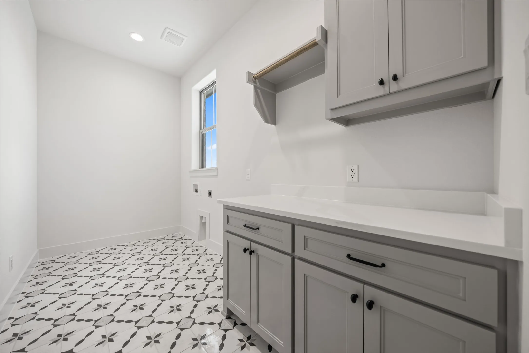 White paneled cabinetry with black hardware, white countertops, and patterned floor tile