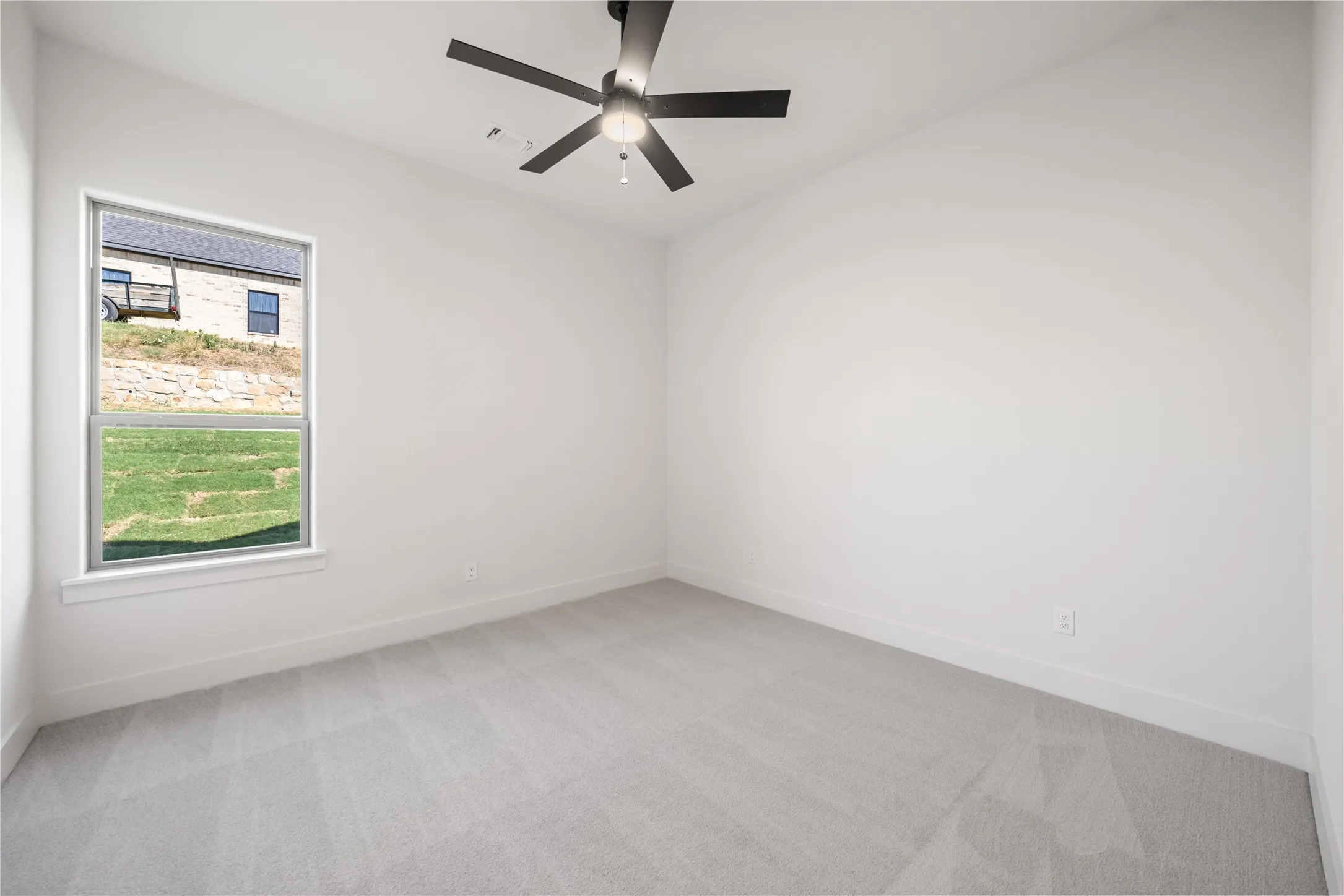 Light gray carpet, crisp white walls, and a contemporary black ceiling fan
