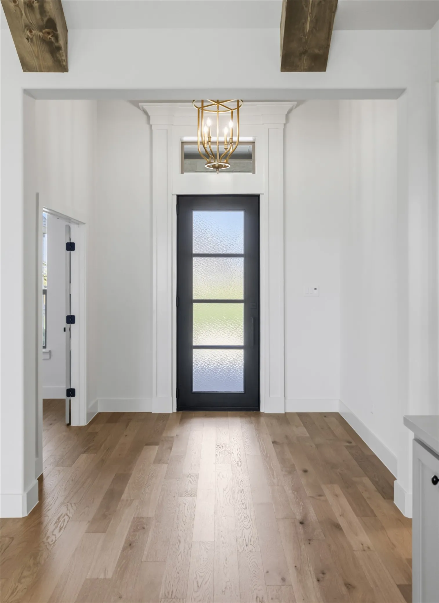 Entryway featuring wood-finish flooring, a black front door with privacy glass panels, and a decorative overhead light fixture