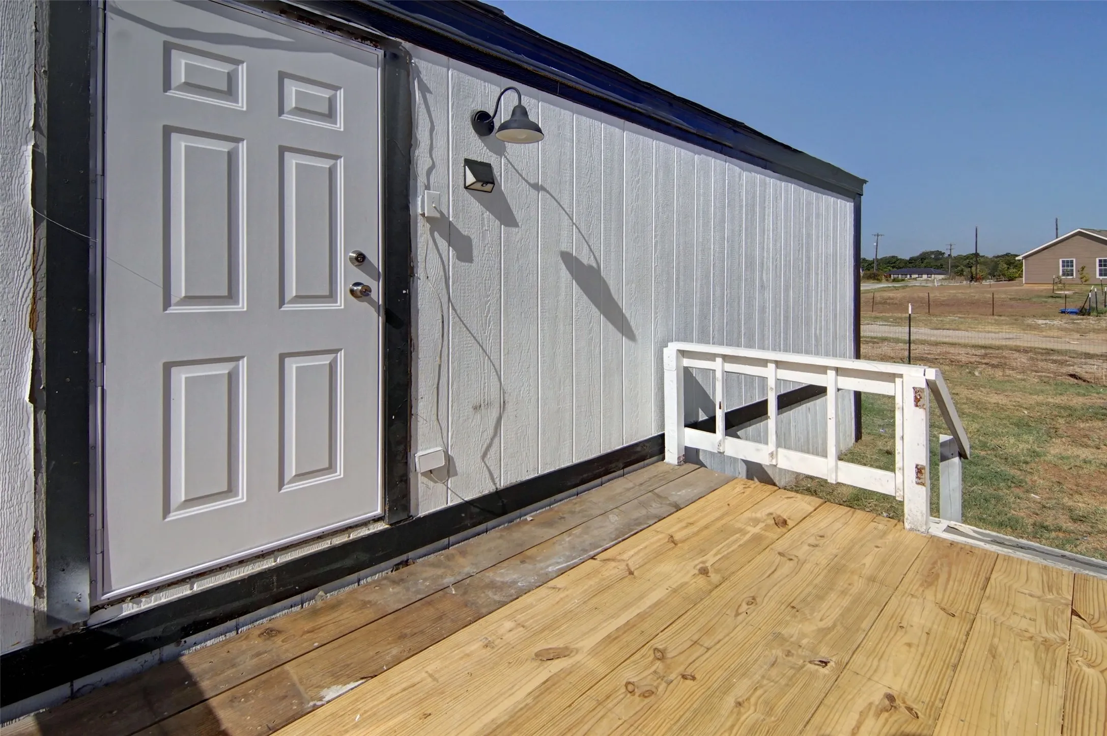 White paneled exterior with a wood deck and a white painted railing
