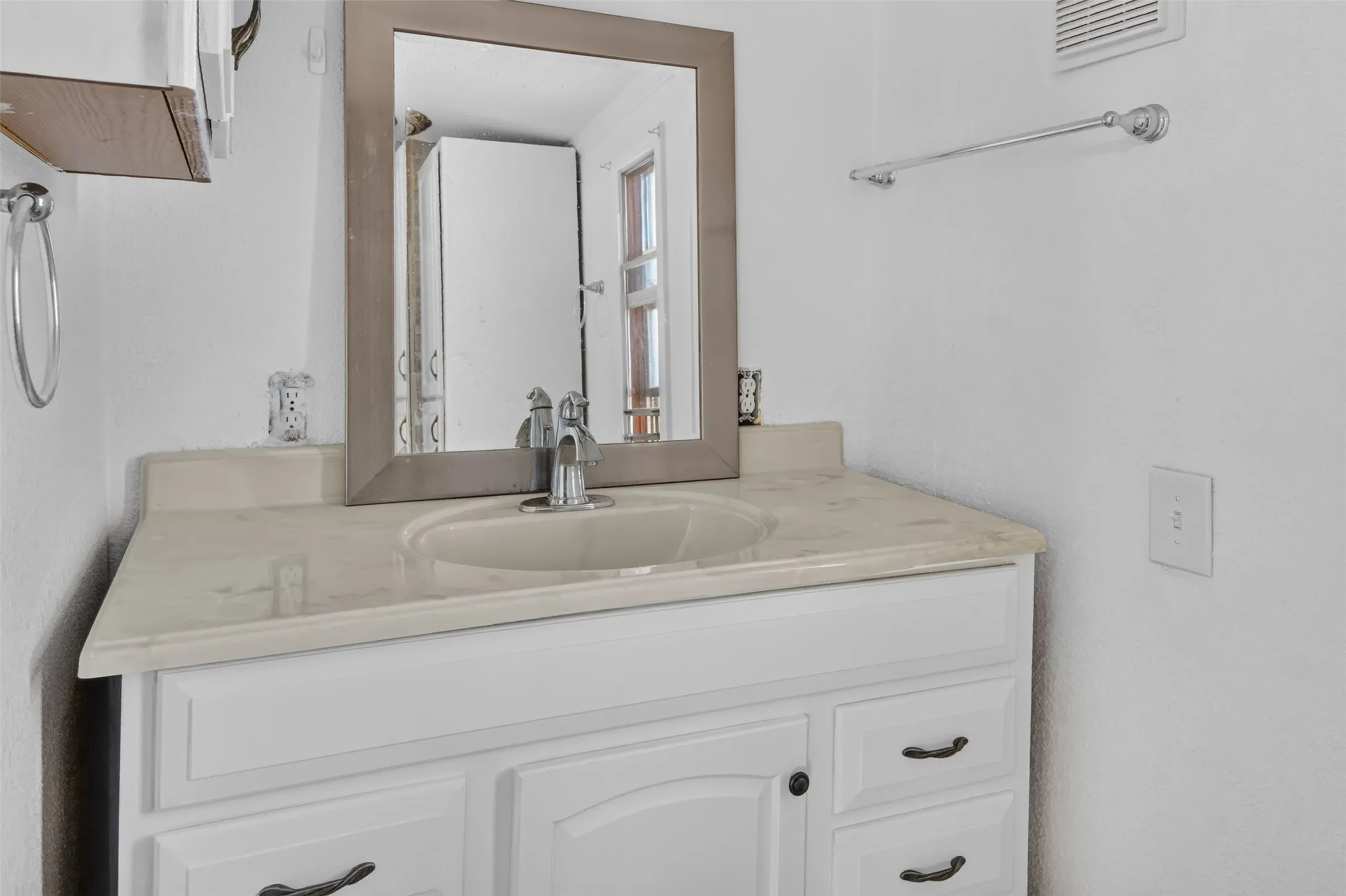 White vanity with a neutral-toned countertop and an integrated sink, featuring a chrome faucet