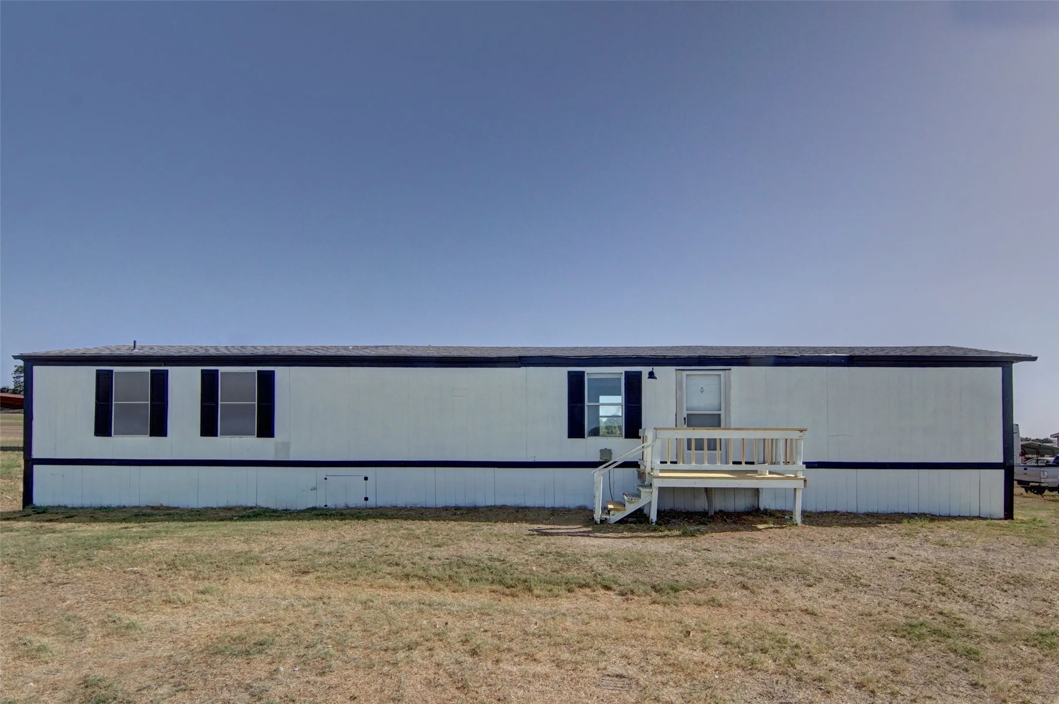 Single-story residential structure with light-colored siding and dark trim