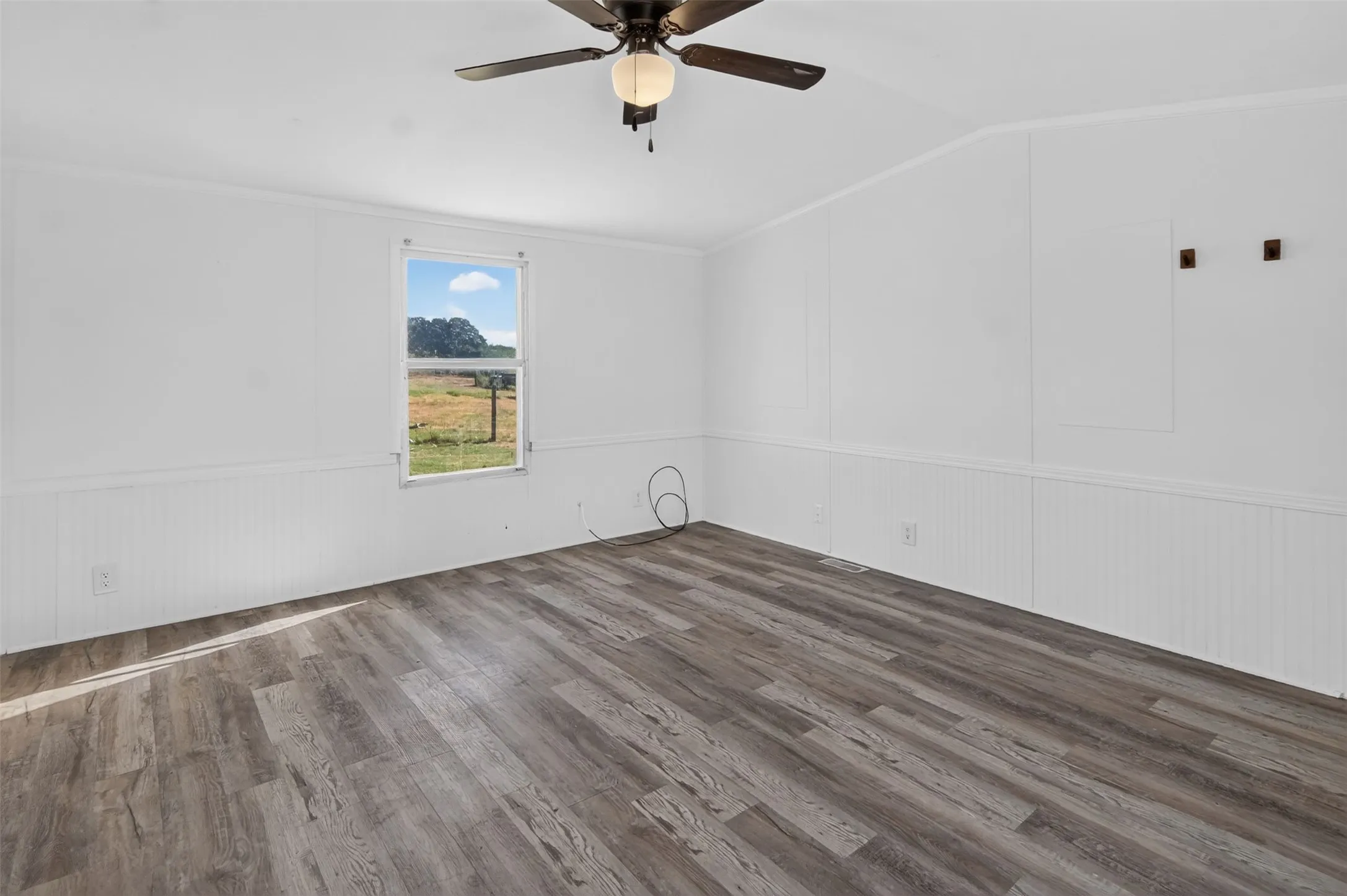 Wood-finish flooring, white walls, white beadboard wainscoting, and a ceiling fan with integrated lighting