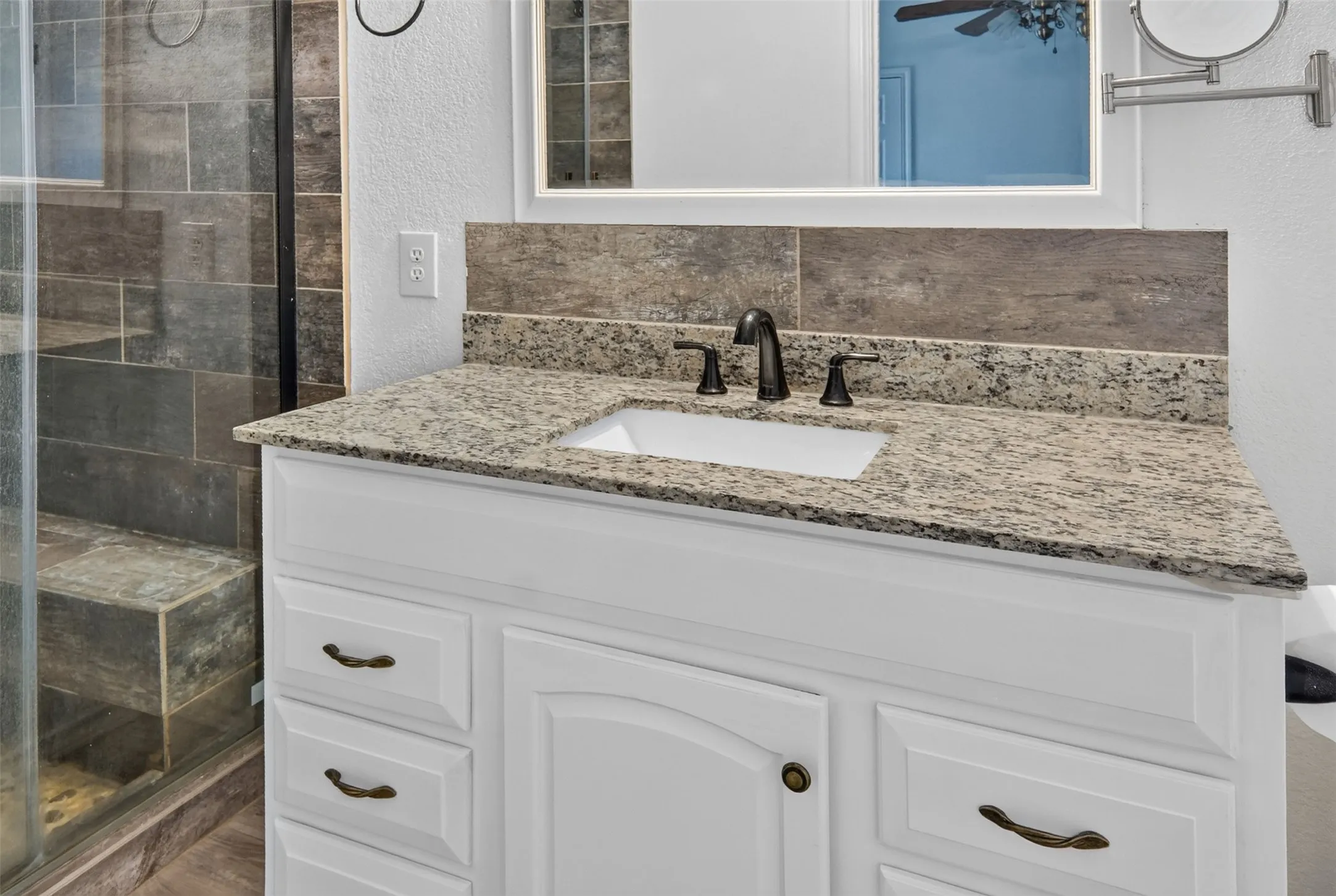 White vanity with bronze-finish hardware, light-toned countertop, and bronze-finish faucet