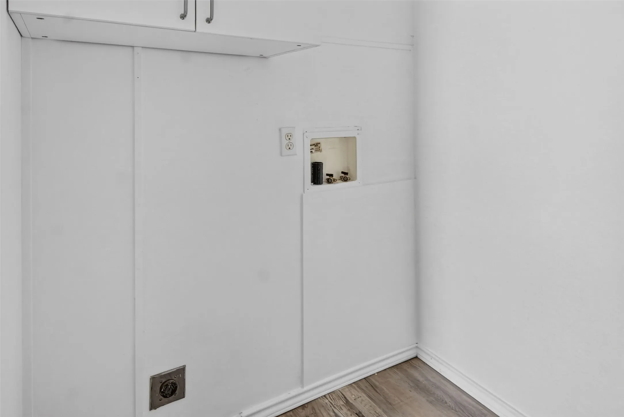 Built-in upper cabinetry, panelized walls, wood-finish flooring, and utility hookups
