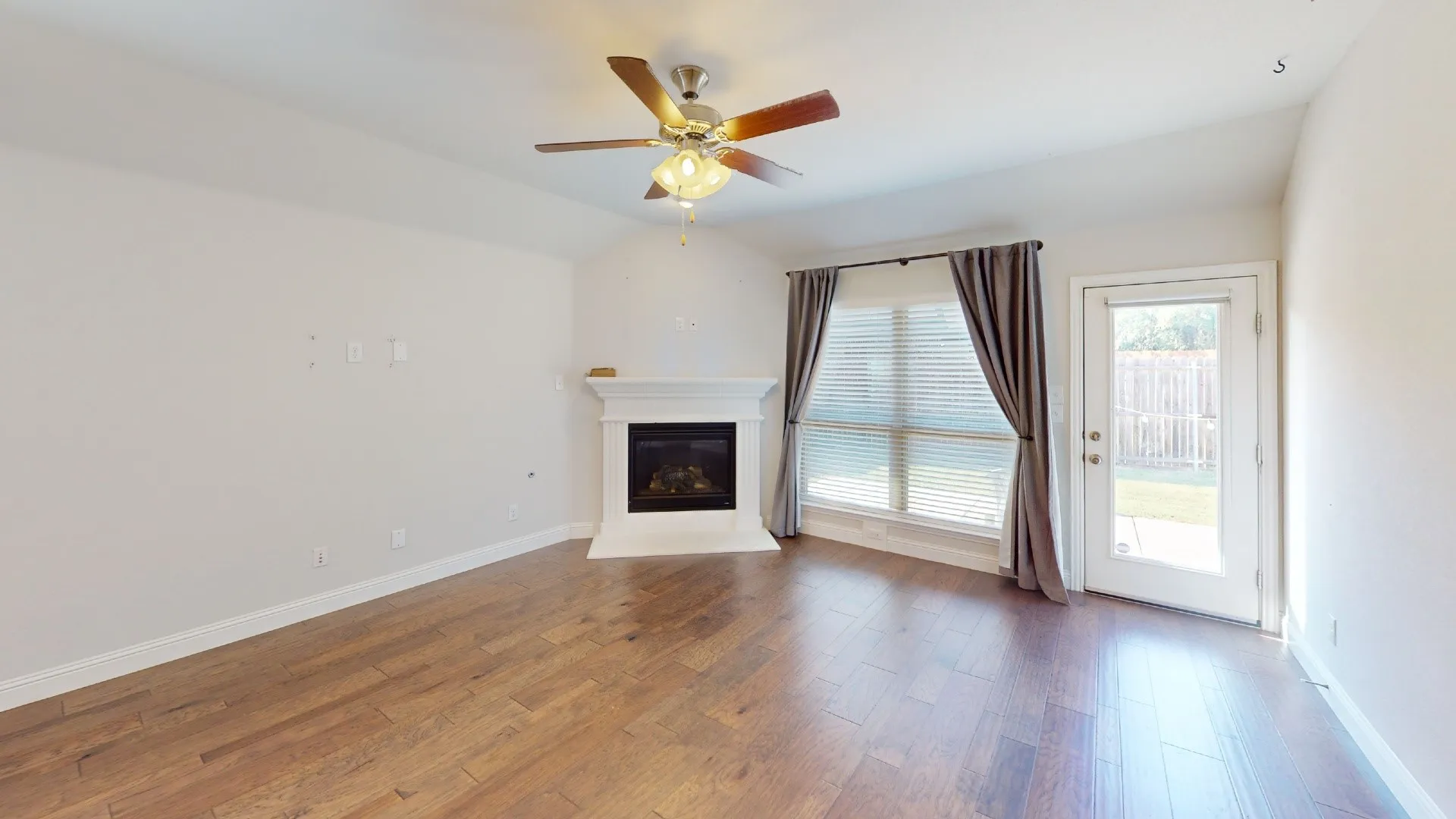 Wood-finish flooring, white walls, and a fireplace with a white mantel