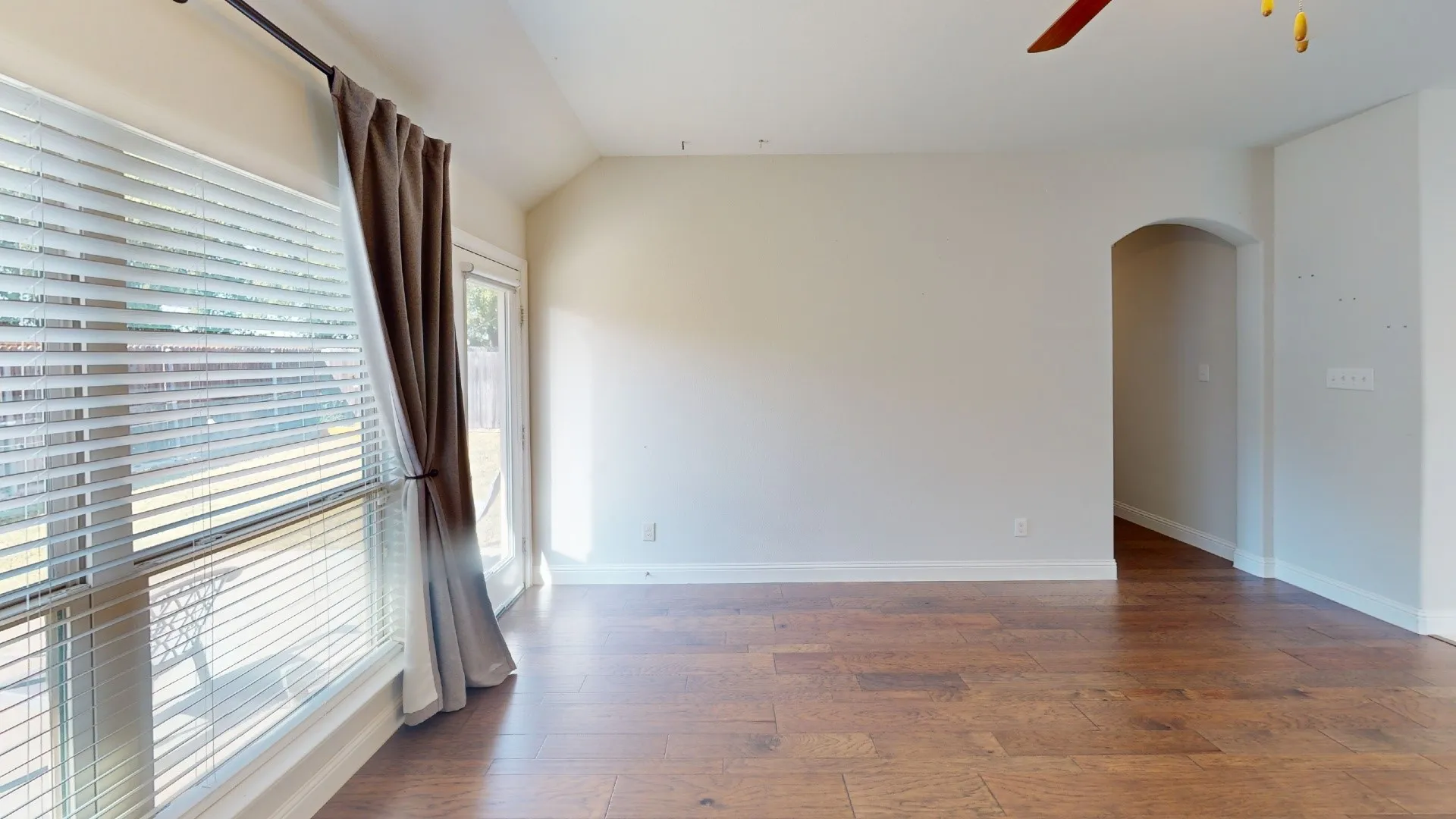Wood-finish flooring, vaulted ceilings, and a large window with blinds
