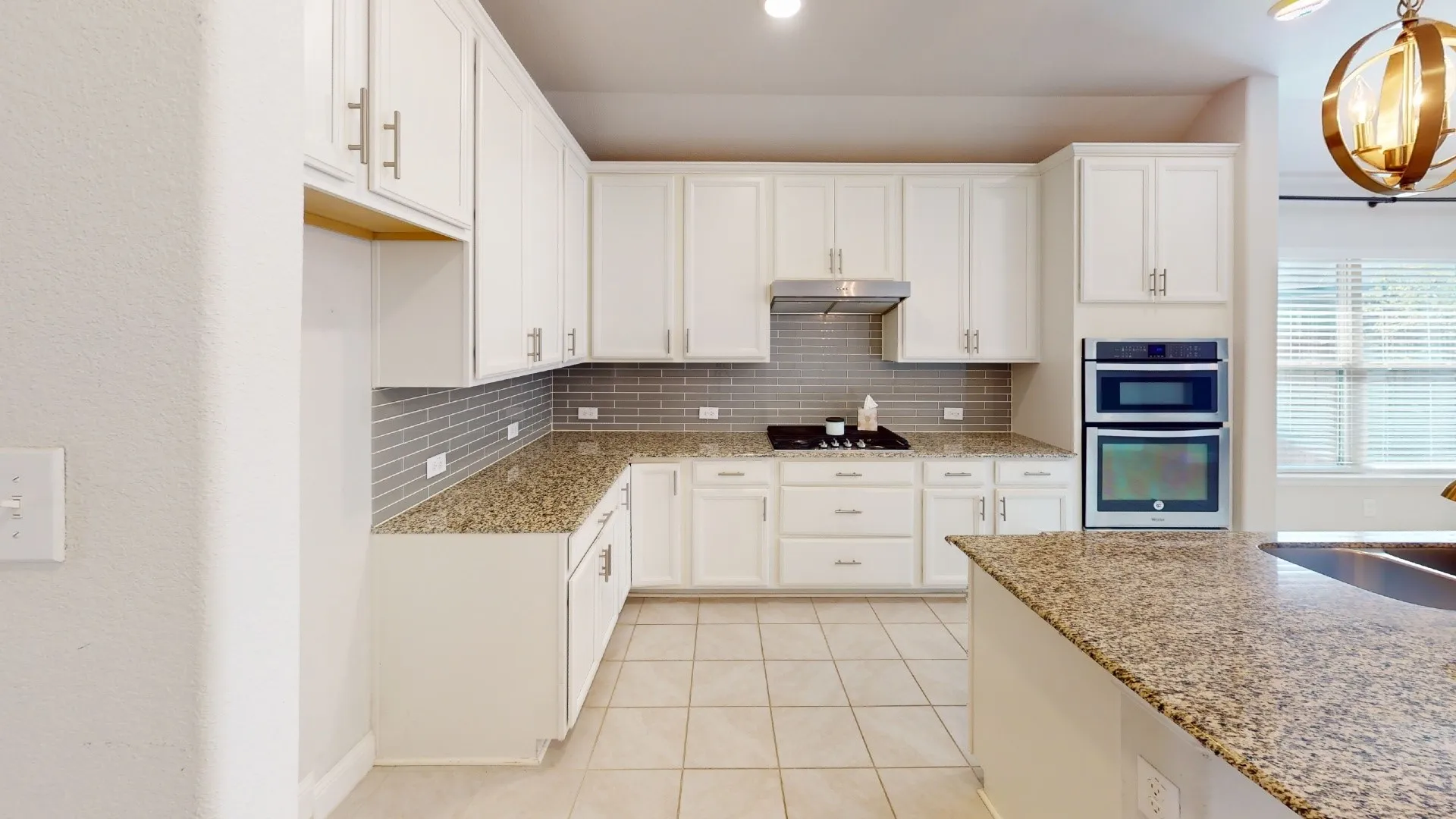 Kitchen featuring white cabinetry, granite countertops, tile flooring, a gas cooktop with an overhead range hood, and a built-in double oven