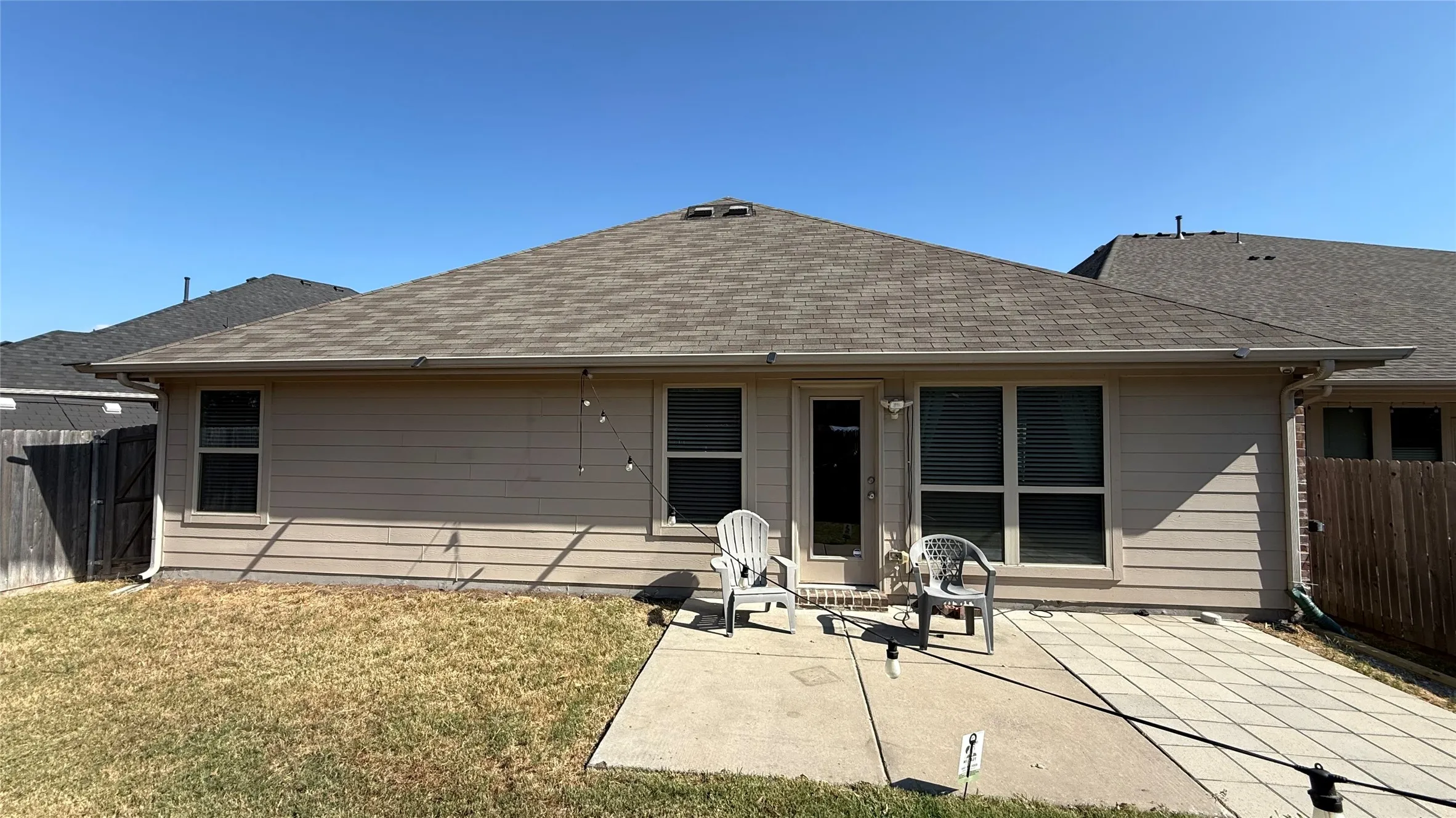 Rear exterior with a concrete patio, a paver patio section, and a fenced perimeter