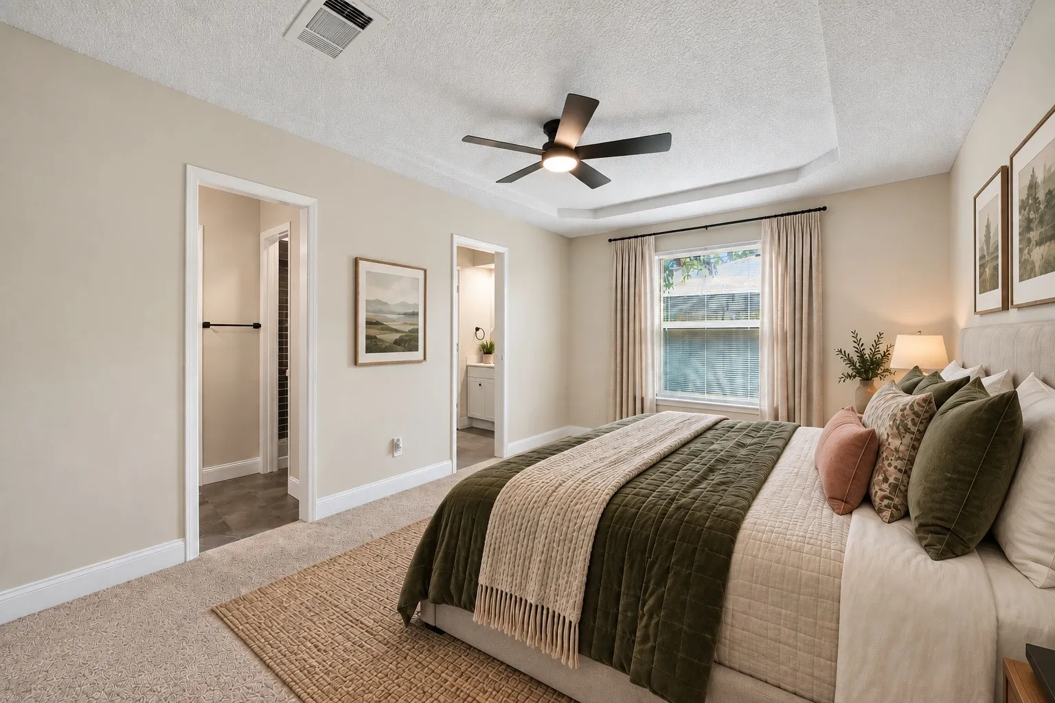 Spacious primary suite featuring a tray ceiling, abundant natural light, and convenient access to the split ensuite bath with His & Hers closets. *Virtually Staged*