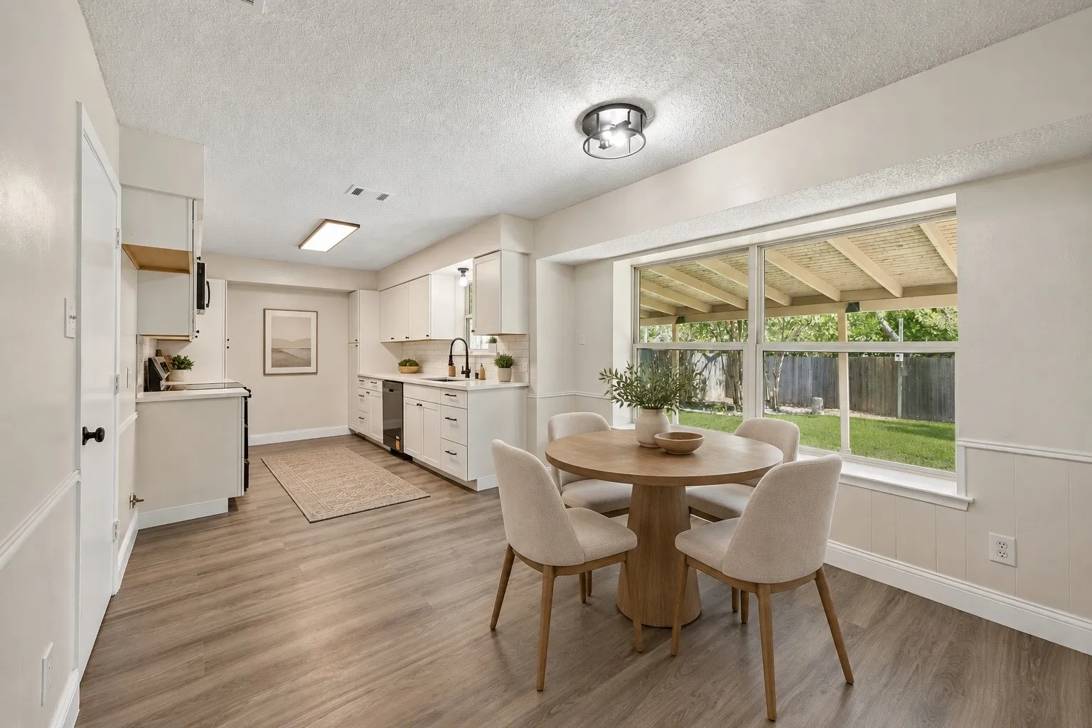 Light-filled kitchen and dining space with modern finishes, generous natural light, and peaceful backyard views- Virtually Staged