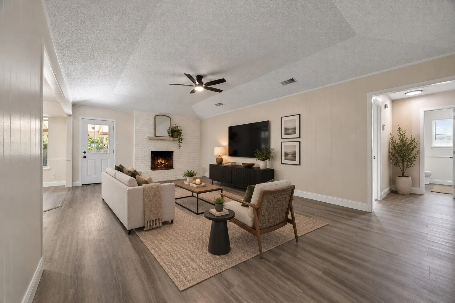 Inviting living space with a charming brick fireplace, vaulted ceiling, and generous layout offering flexibility for everyday living and entertaining. *Virtually Staged*