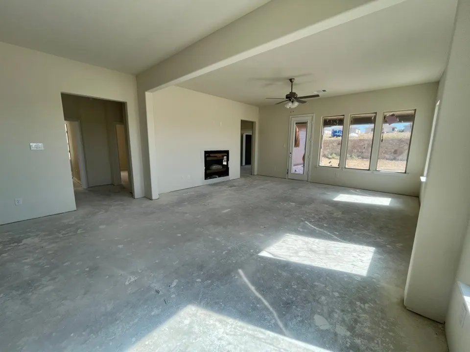 Open-concept living space featuring a built-in fireplace, a ceiling fan, and multiple windows