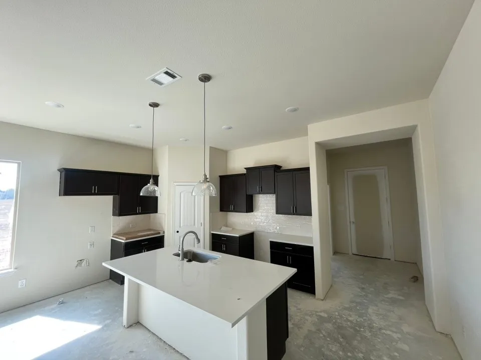 Kitchen featuring dark wood-finish cabinetry, white countertops, and a white subway tile backsplash