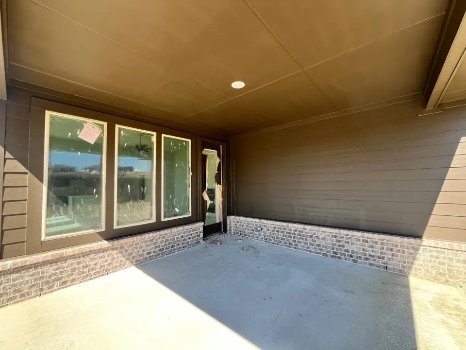 Covered patio featuring a concrete surface, brick accent wall, and multiple transom windows