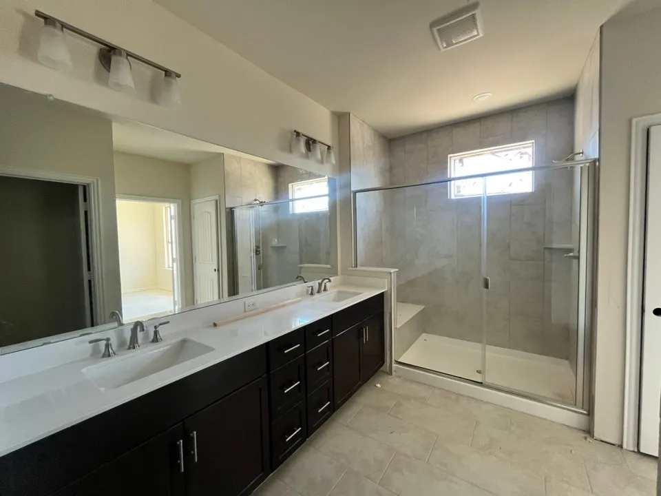 Dual vanity with undermount sinks, stone countertops, and dark wood-finish cabinetry