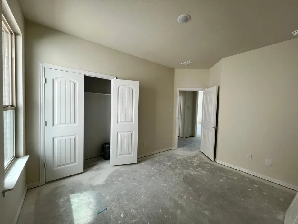 Recessed ceiling lighting, angled ceiling detail, window with trim, built-in closet with panel doors, neutral wall tones