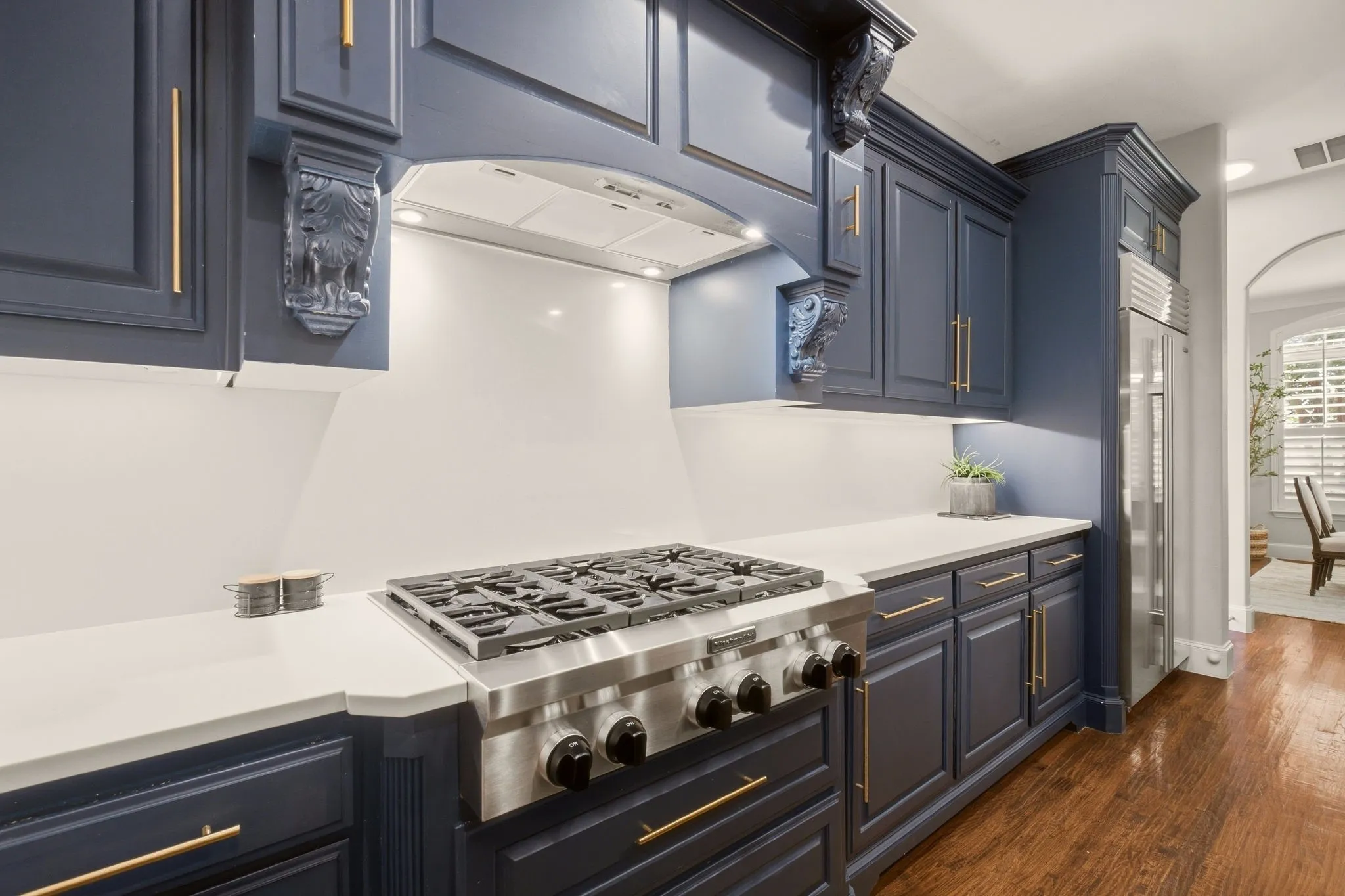 Commercial grade 6-burner gas cooktop is flanked by spice rack pull outs between the corbels.