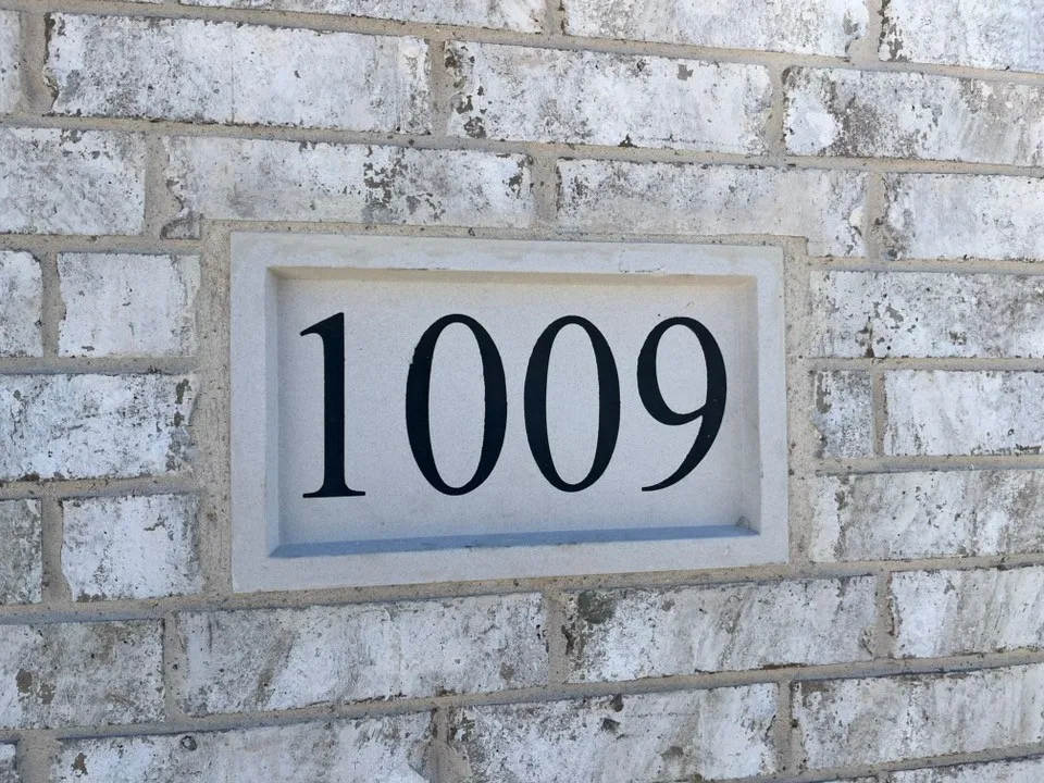 White-washed brick exterior featuring a recessed house number plaque