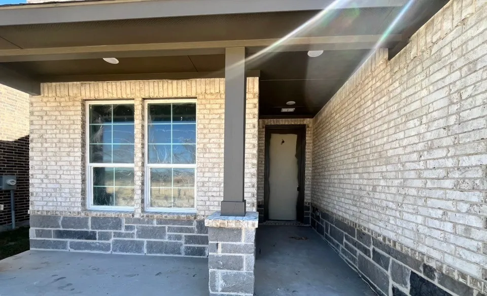 Covered entry with two-tone brick and stone facade, flanked by multi-pane windows