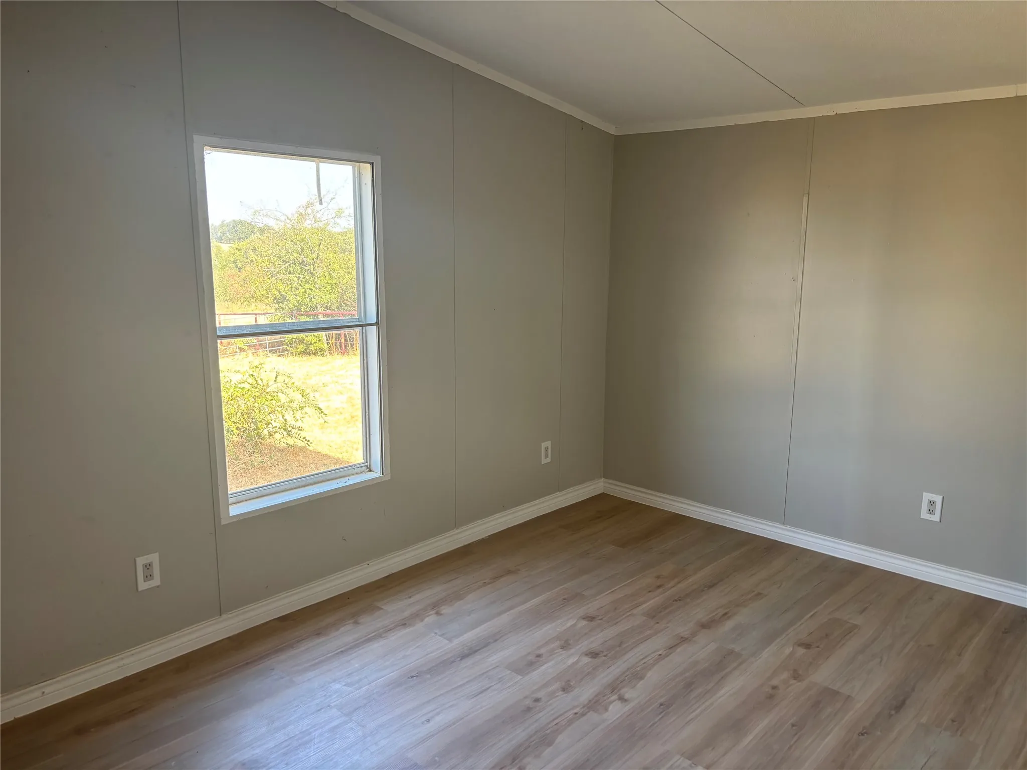 Wood-finish flooring with light neutral wall panels and white trim