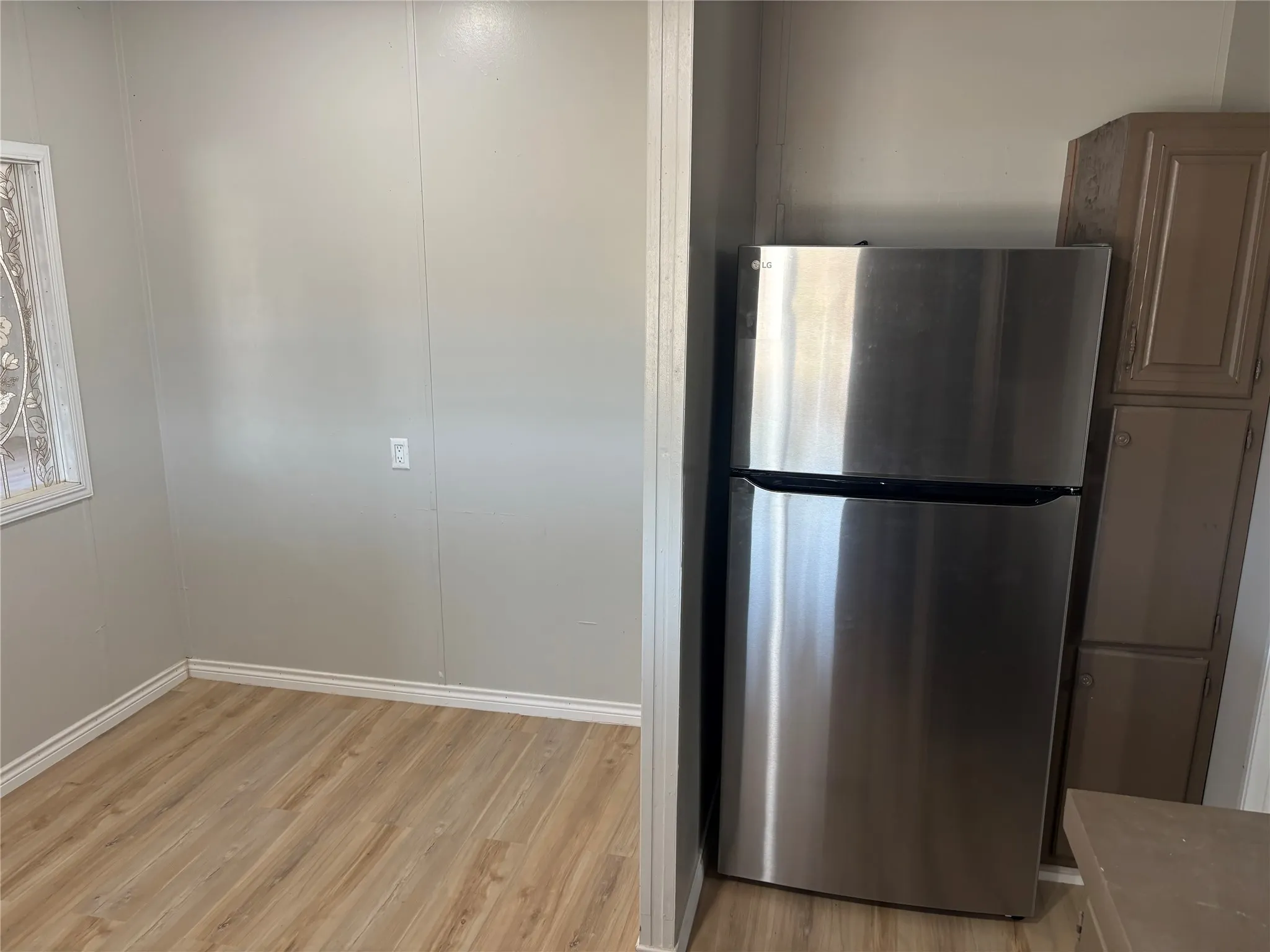Wood-finish flooring with white baseboards and light-toned wall paneling