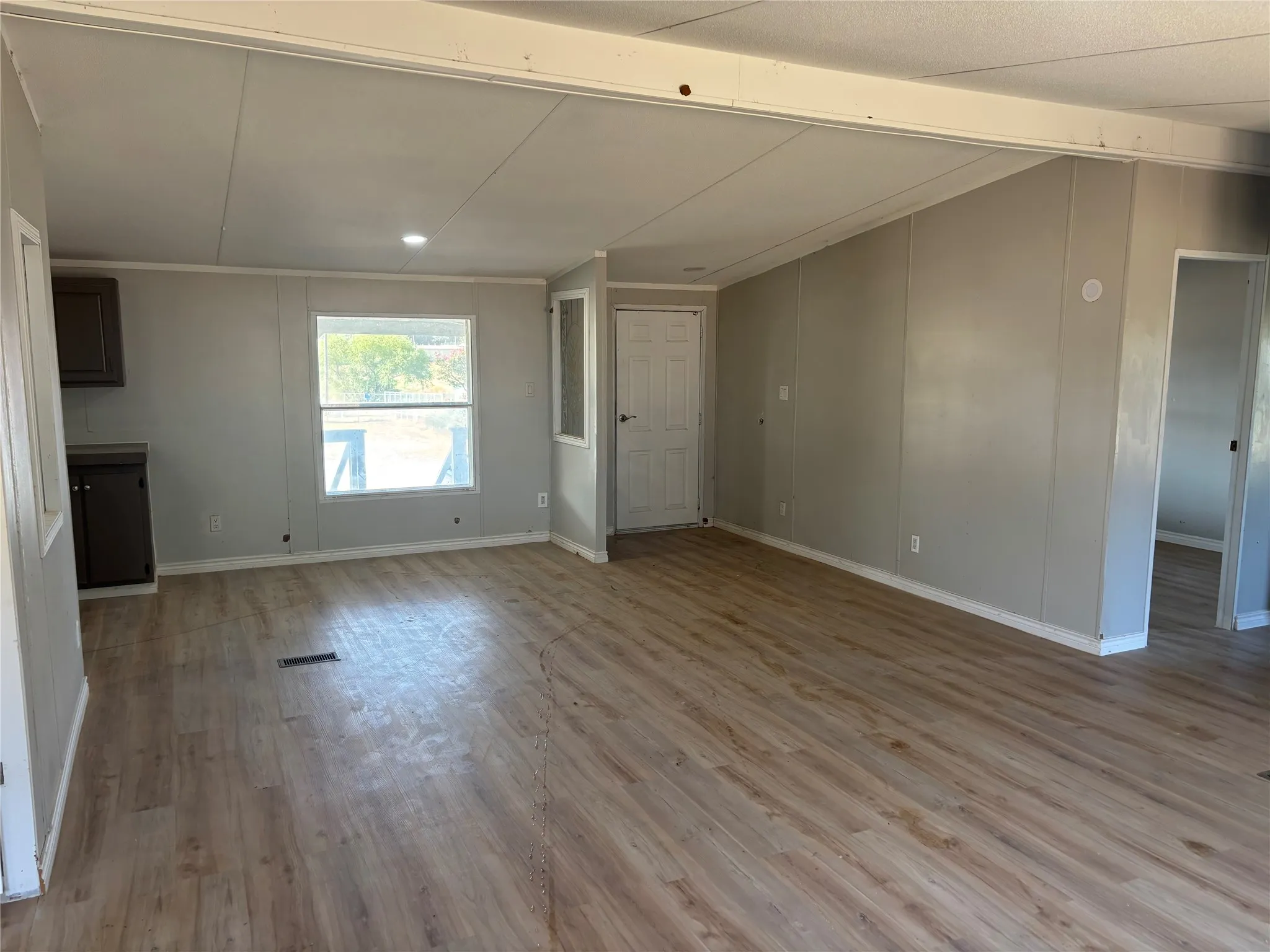 Wood-finish flooring throughout, light gray wall paneling, and an egress door