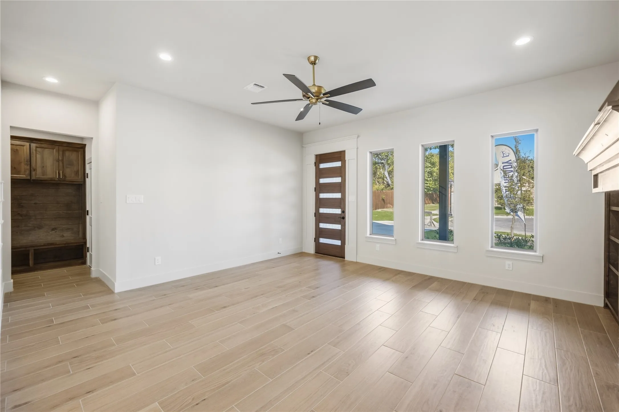 Light wood-finish flooring, recessed lighting, and a ceiling fan with brass accents