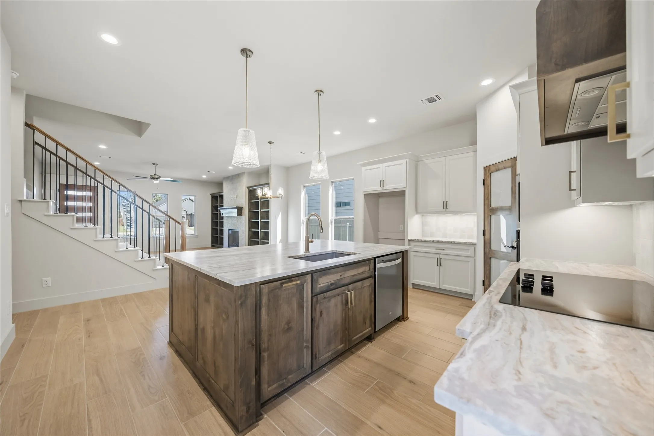 Spacious kitchen featuring an expansive center island with an undermount sink, built-in dishwasher, and pendant lighting