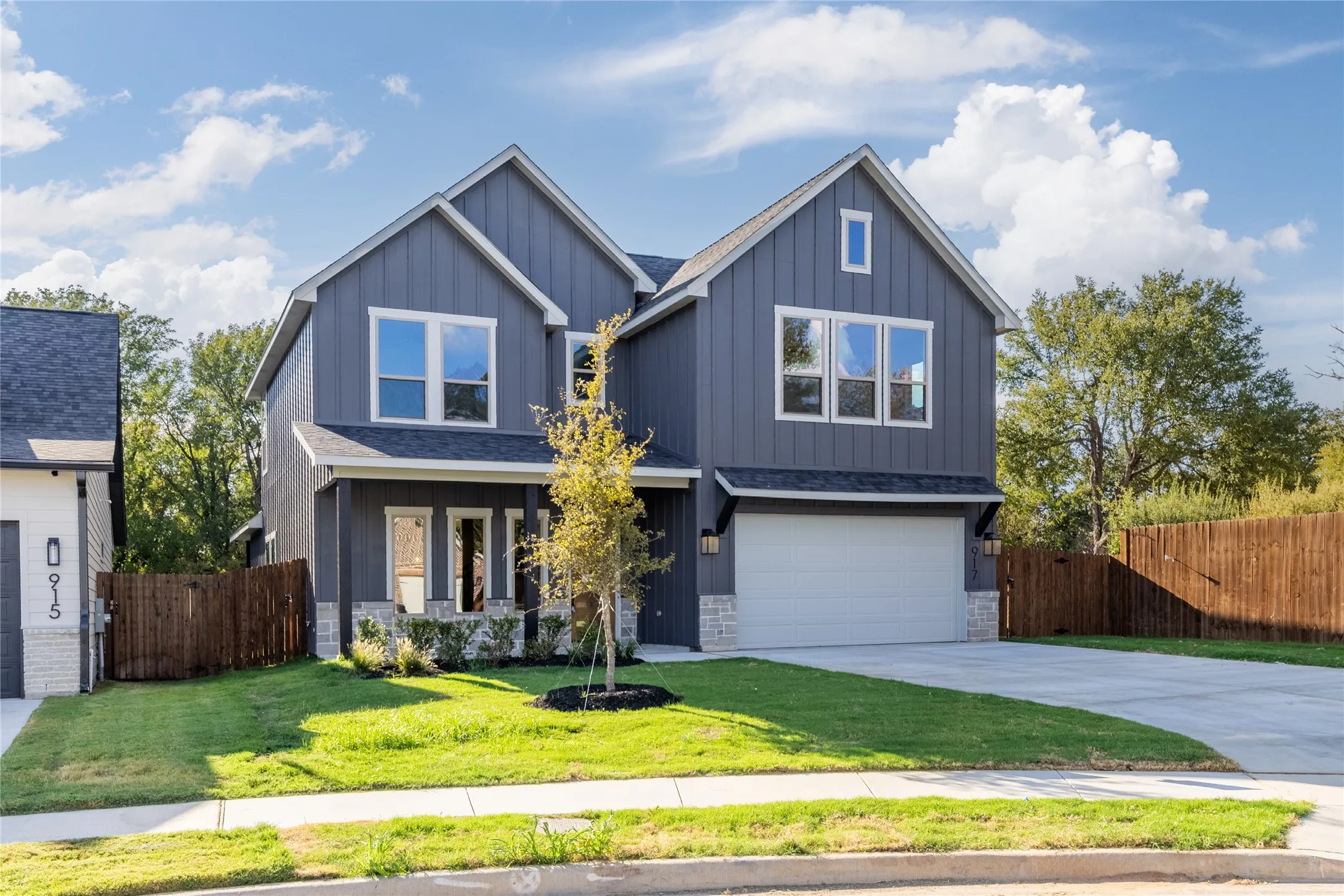Contemporary two-story exterior with board-and-batten siding, stone accents, and an attached two-car garage