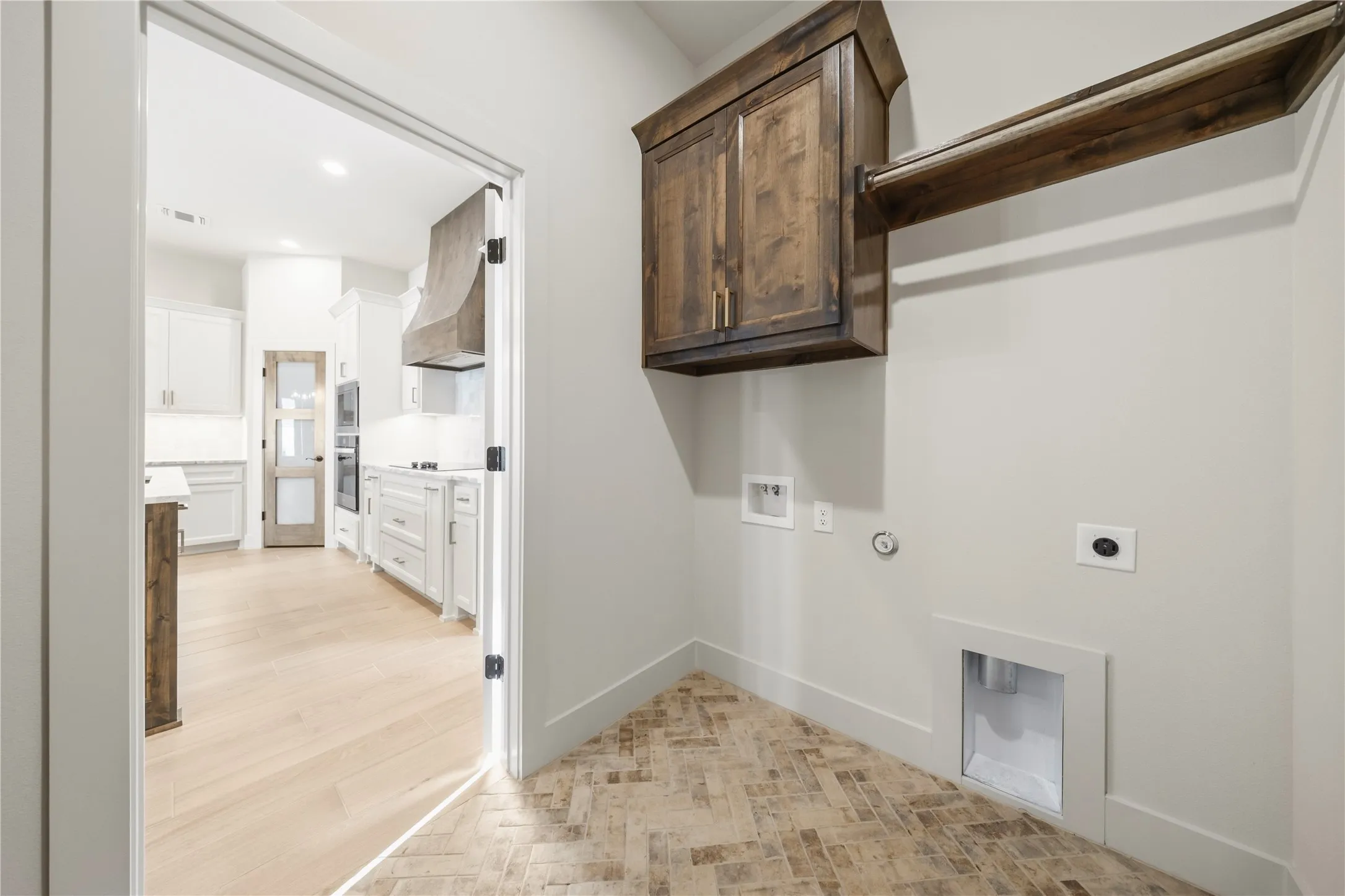 Laundry area featuring wood-finish herringbone flooring, wood cabinetry, and a wood-finish hanging rod