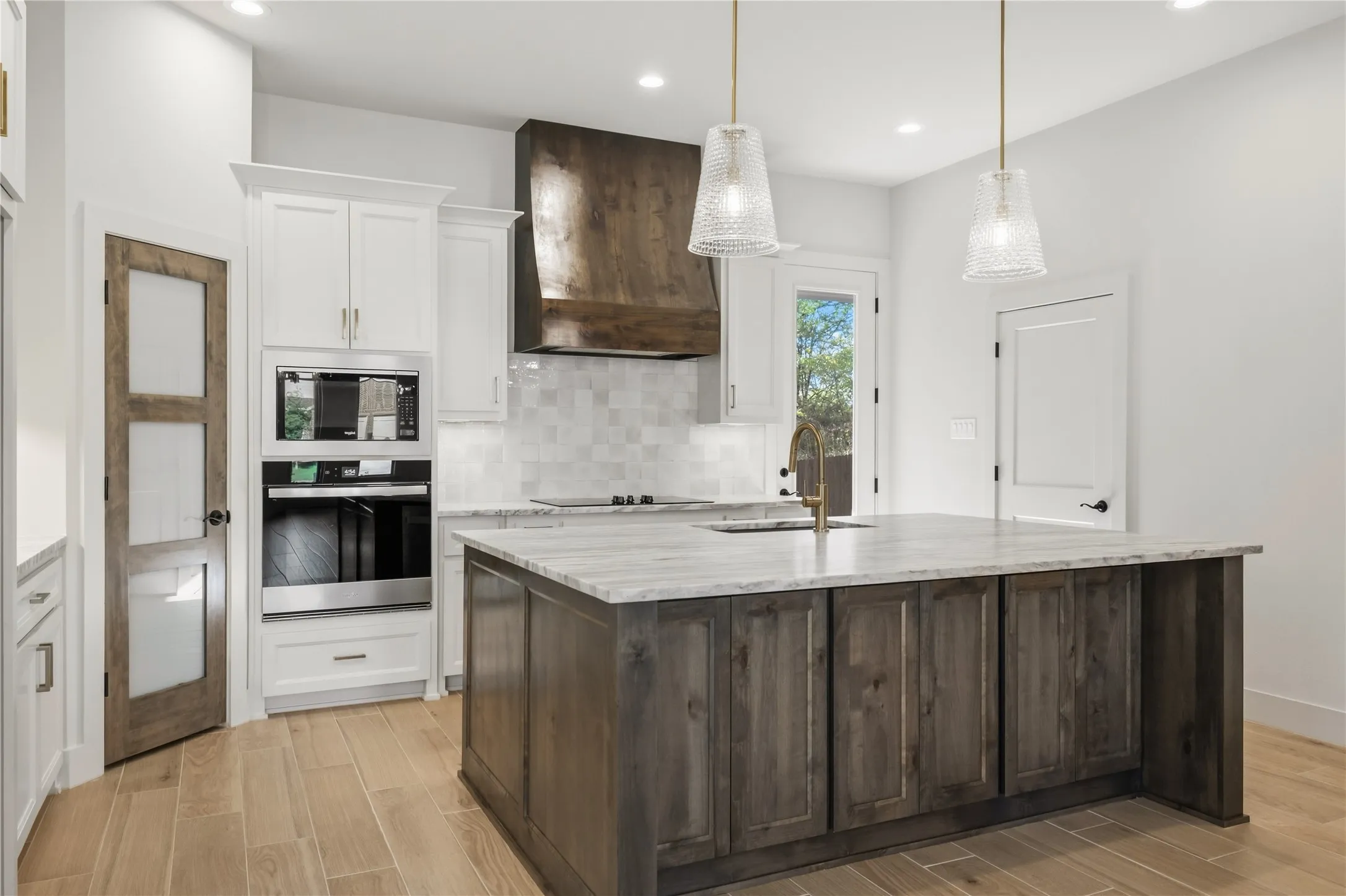 Kitchen featuring a center island with under-counter storage, stone countertops, a bronze-finish kitchen faucet, and recessed lighting