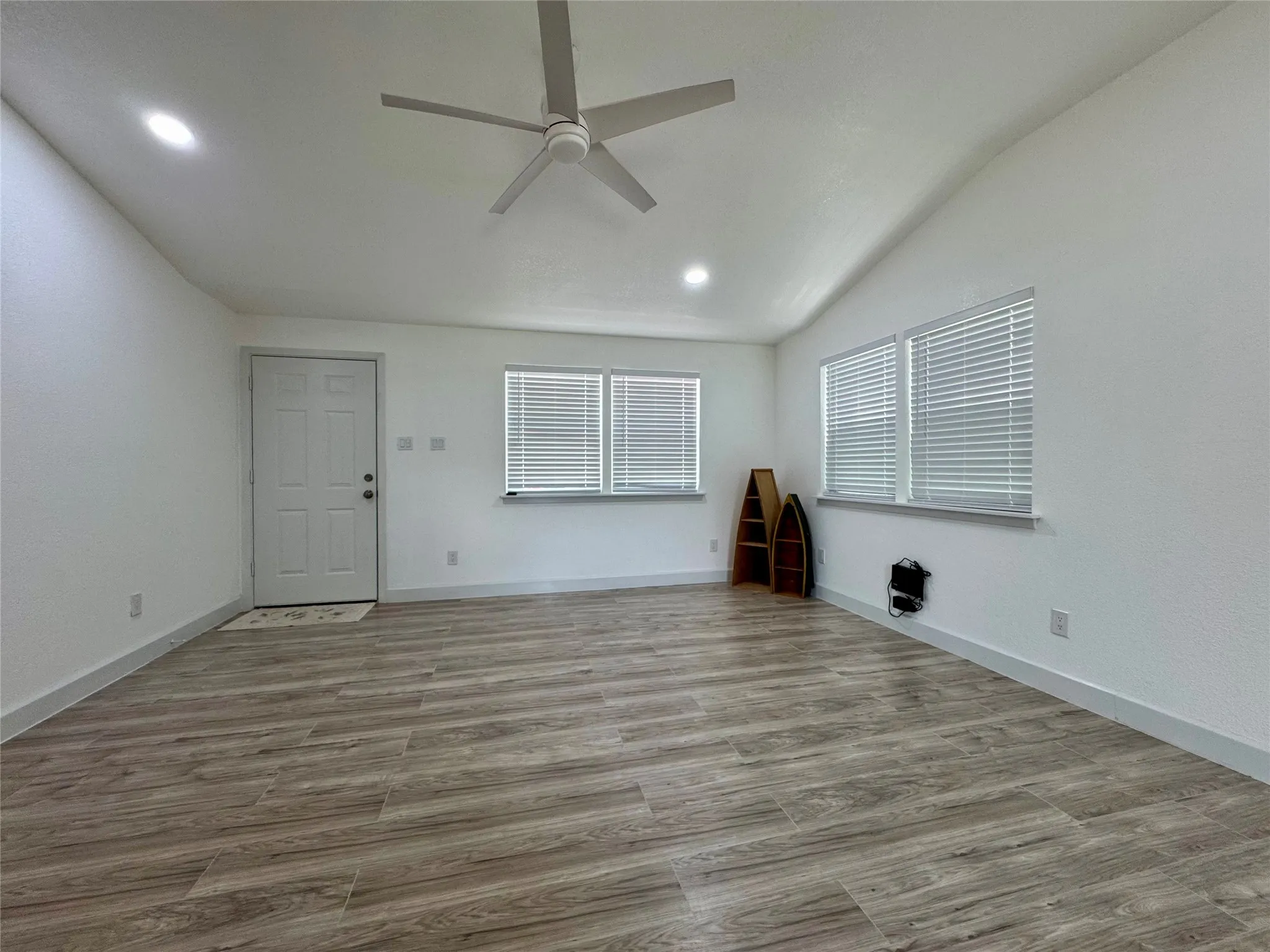 Unfurnished room featuring ceiling fan, recessed lighting, wood finished floors, and lofted ceiling