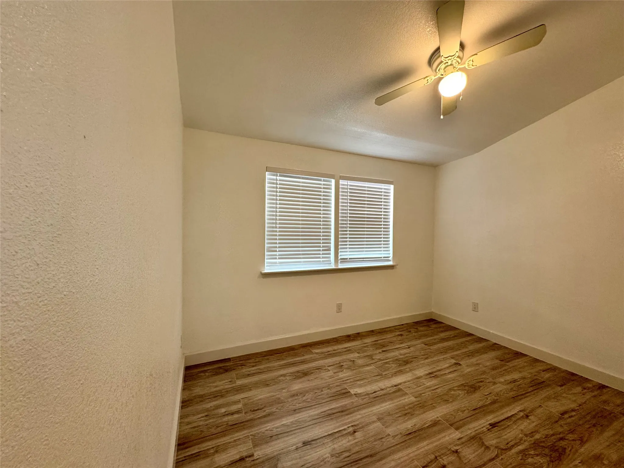 Spare room with wood finished floors and a ceiling fan