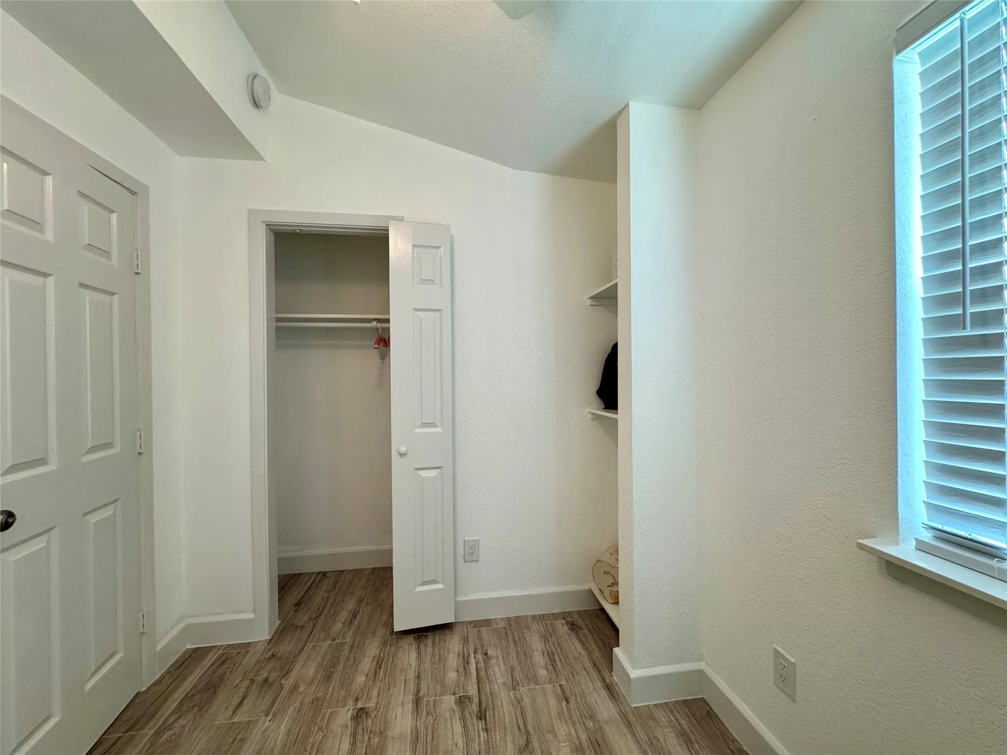 Unfurnished bedroom with wood finished floors and a closet