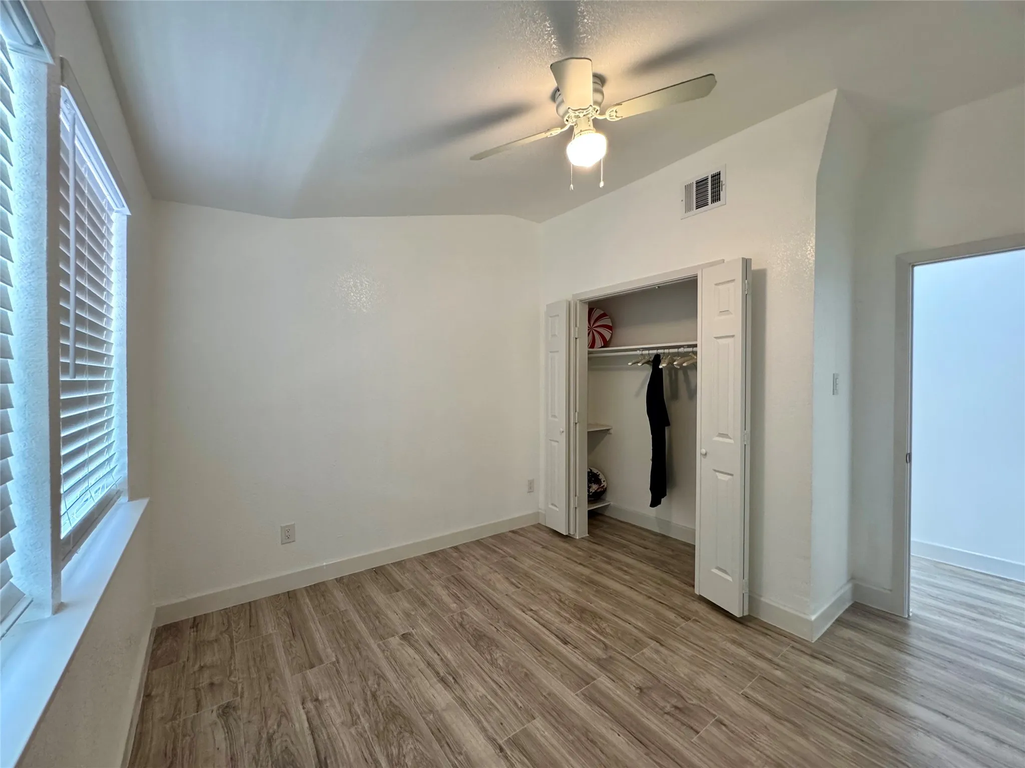 Unfurnished bedroom featuring wood finished floors, ceiling fan, and a closet