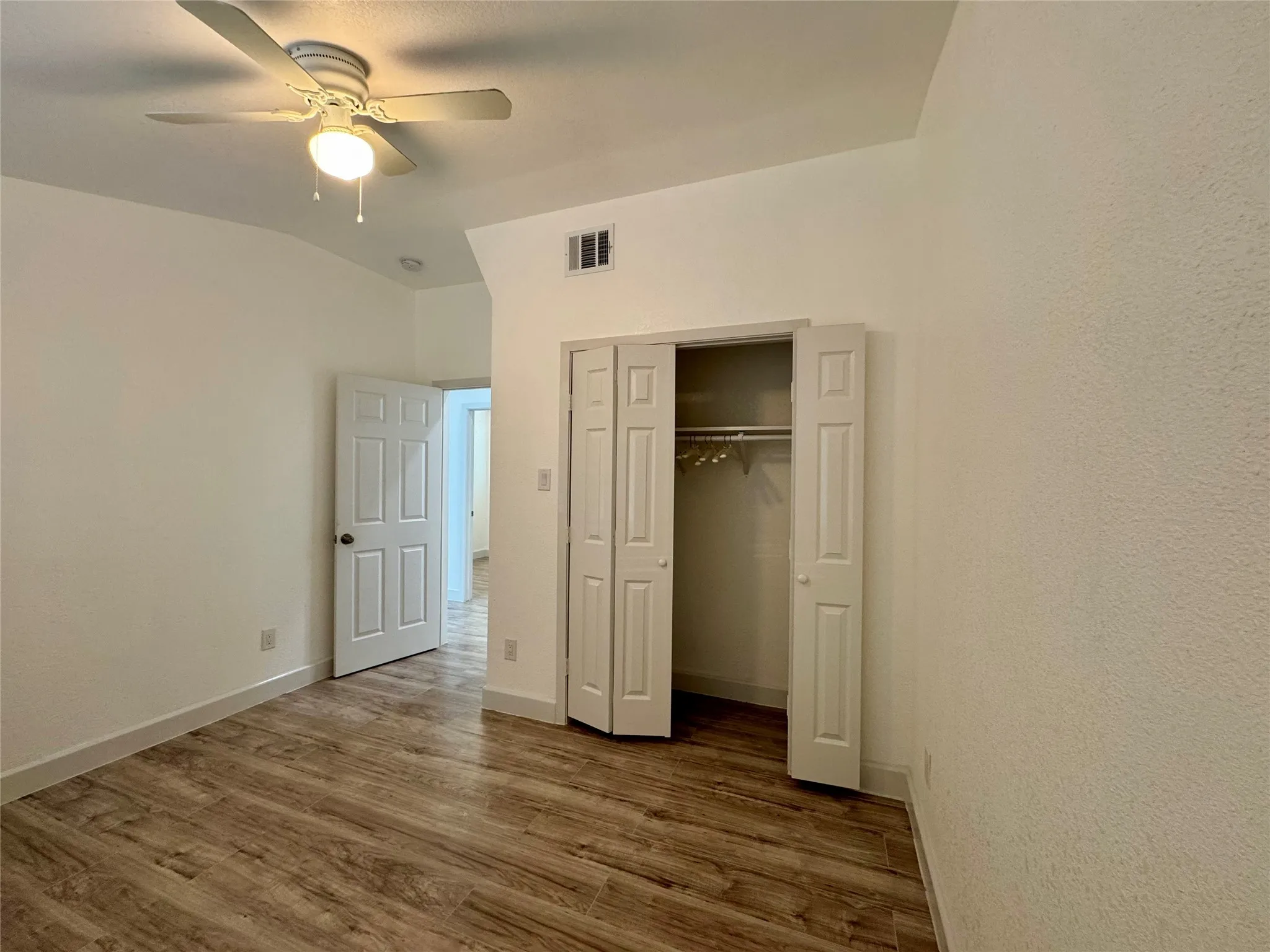Unfurnished bedroom featuring wood finished floors, a closet, a ceiling fan, and lofted ceiling