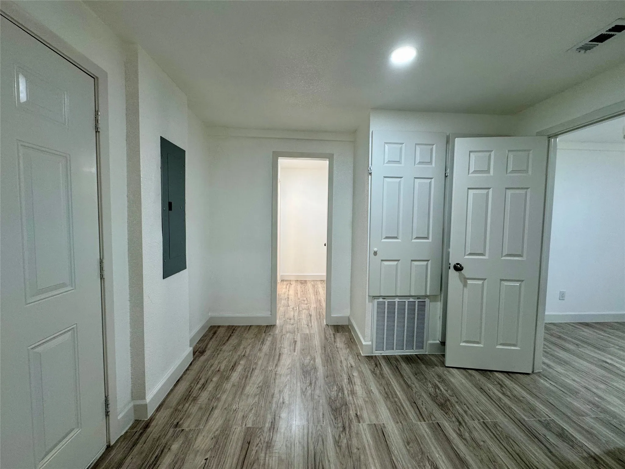 Hallway with wood finished floors and electric panel
