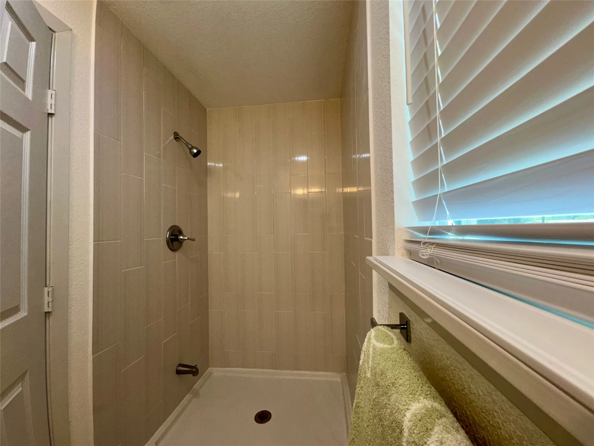 Bathroom featuring tiled shower and a textured ceiling