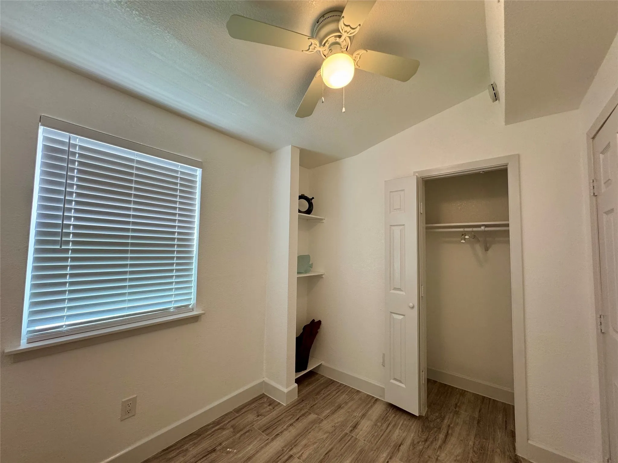 Unfurnished bedroom with wood finished floors, a closet, and ceiling fan