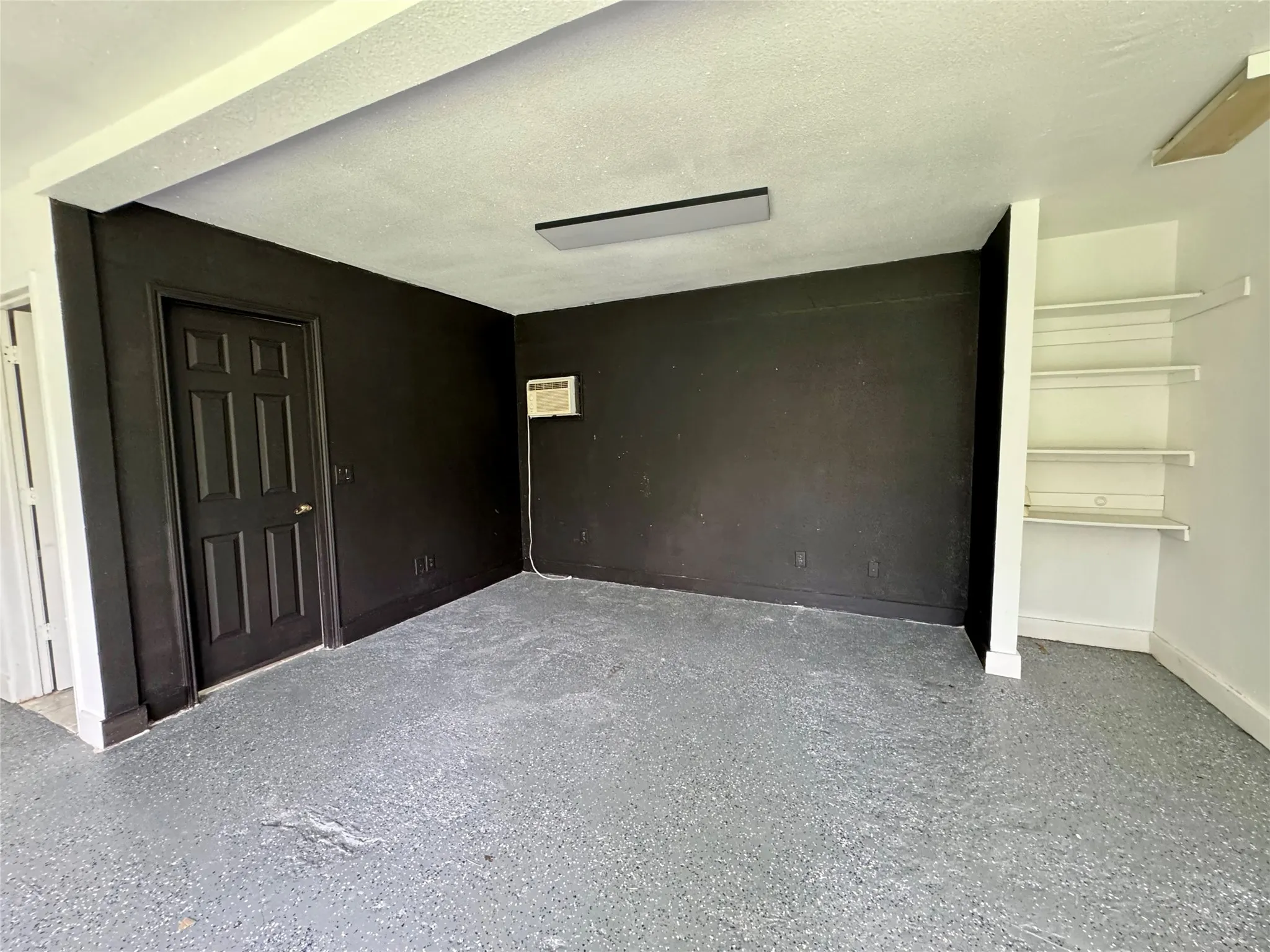 Unfurnished bedroom with a wall mounted AC and speckled floor