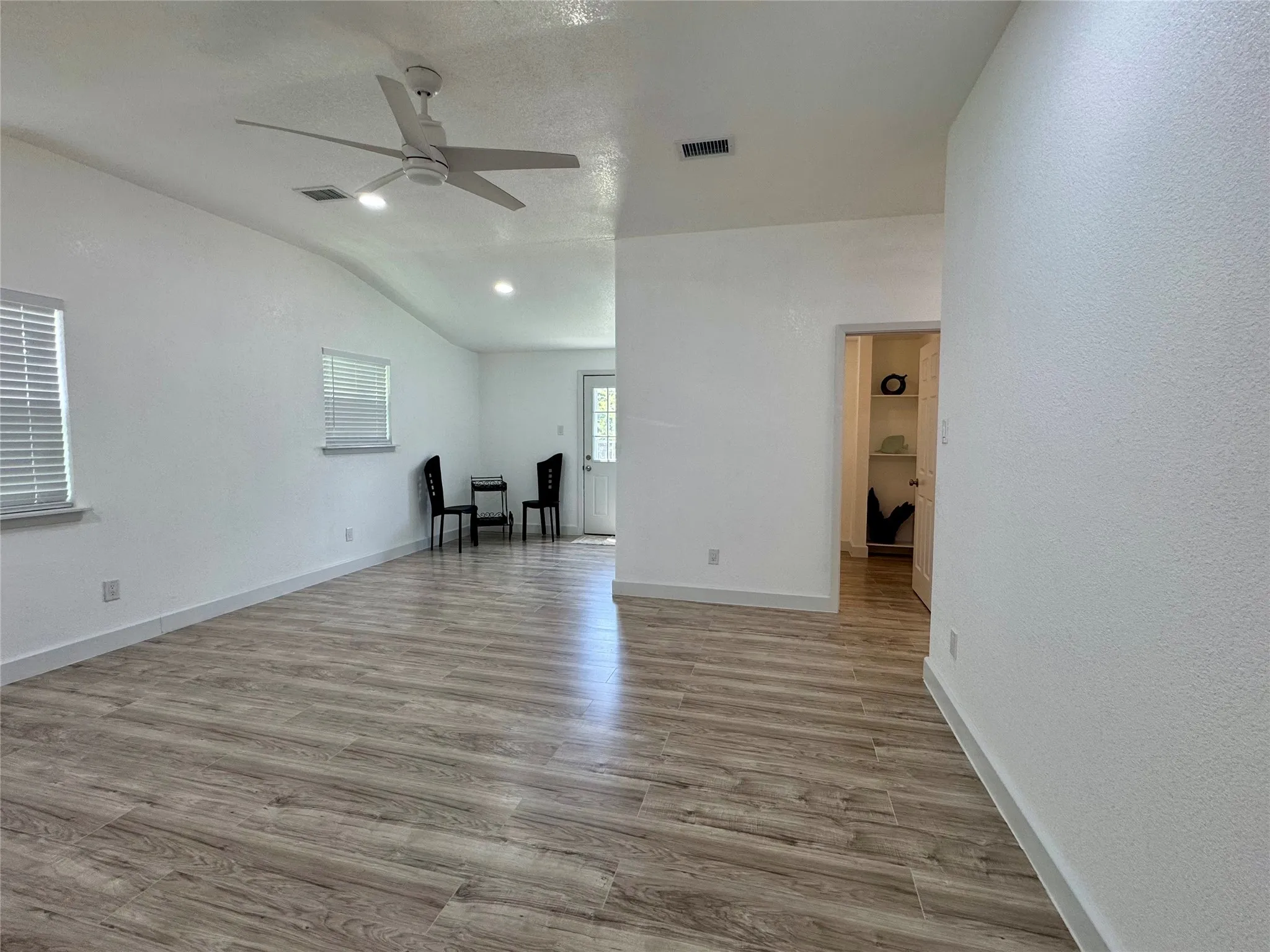 Unfurnished living room with a ceiling fan, vaulted ceiling, wood finished floors, and recessed lighting