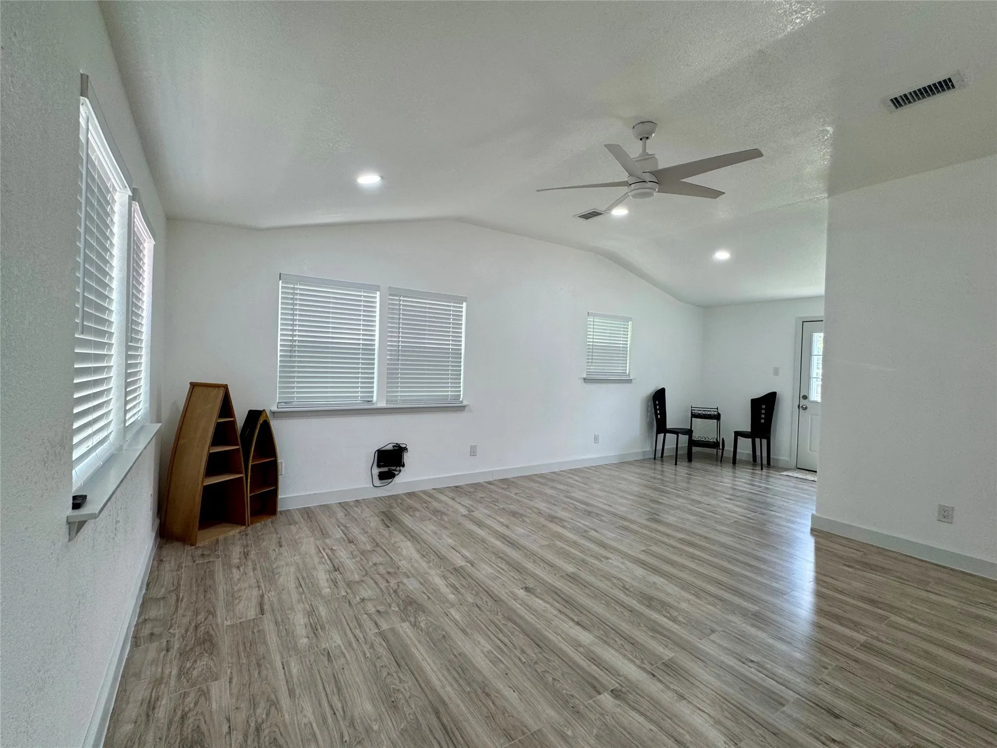 Unfurnished living room featuring wood finished floors, lofted ceiling, ceiling fan, and recessed lighting