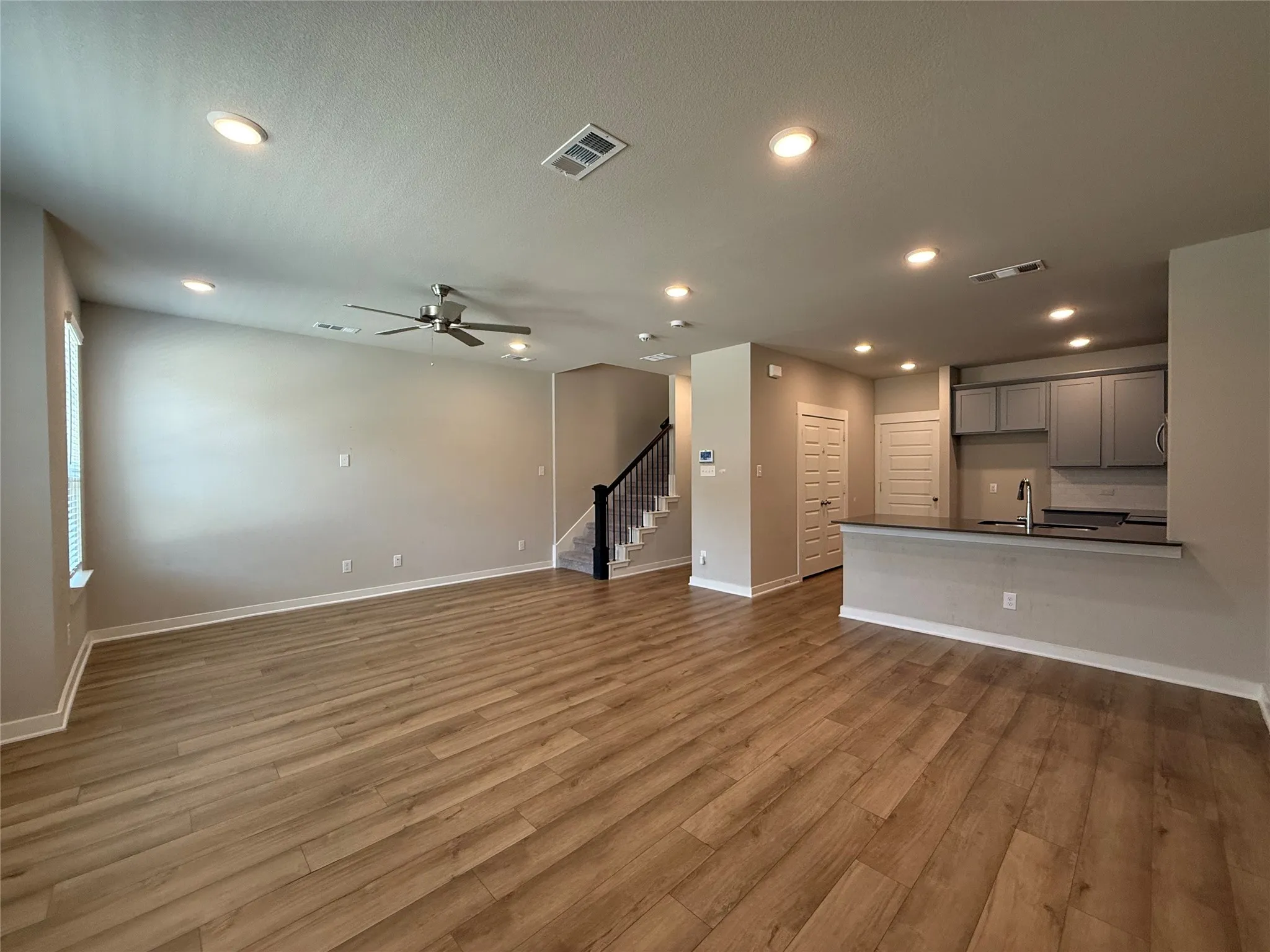 Wood-finish flooring throughout, complemented by recessed lighting and a ceiling fan
