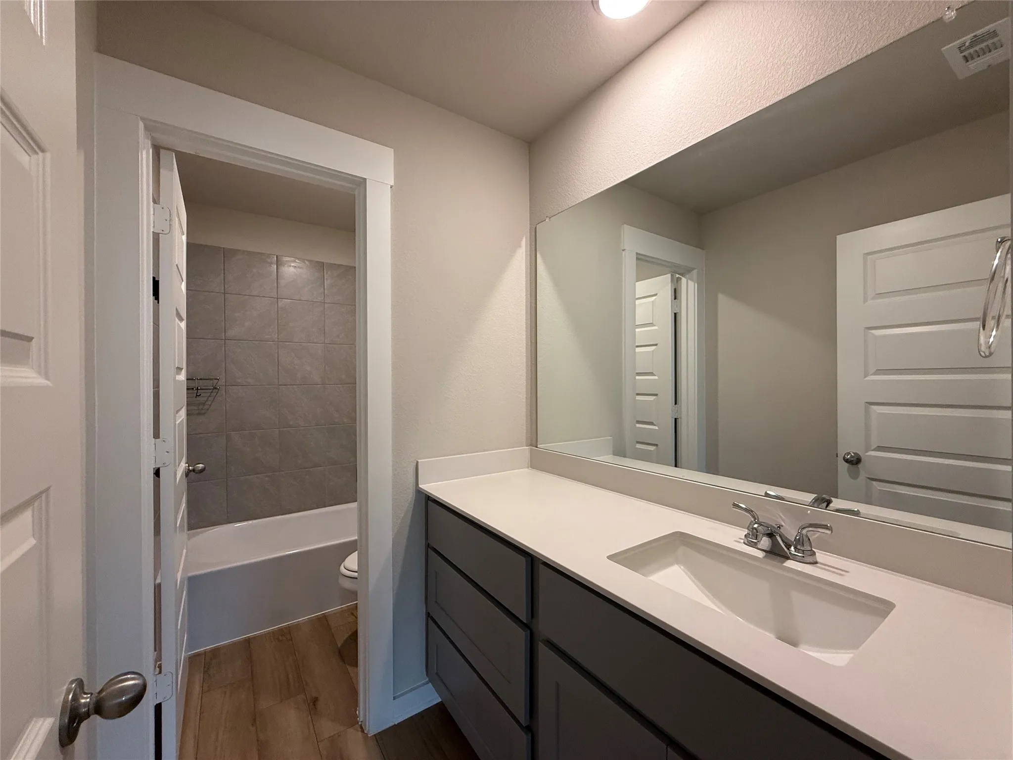 Bathroom featuring a vanity with an integrated sink, polished chrome faucet, and expansive mirror