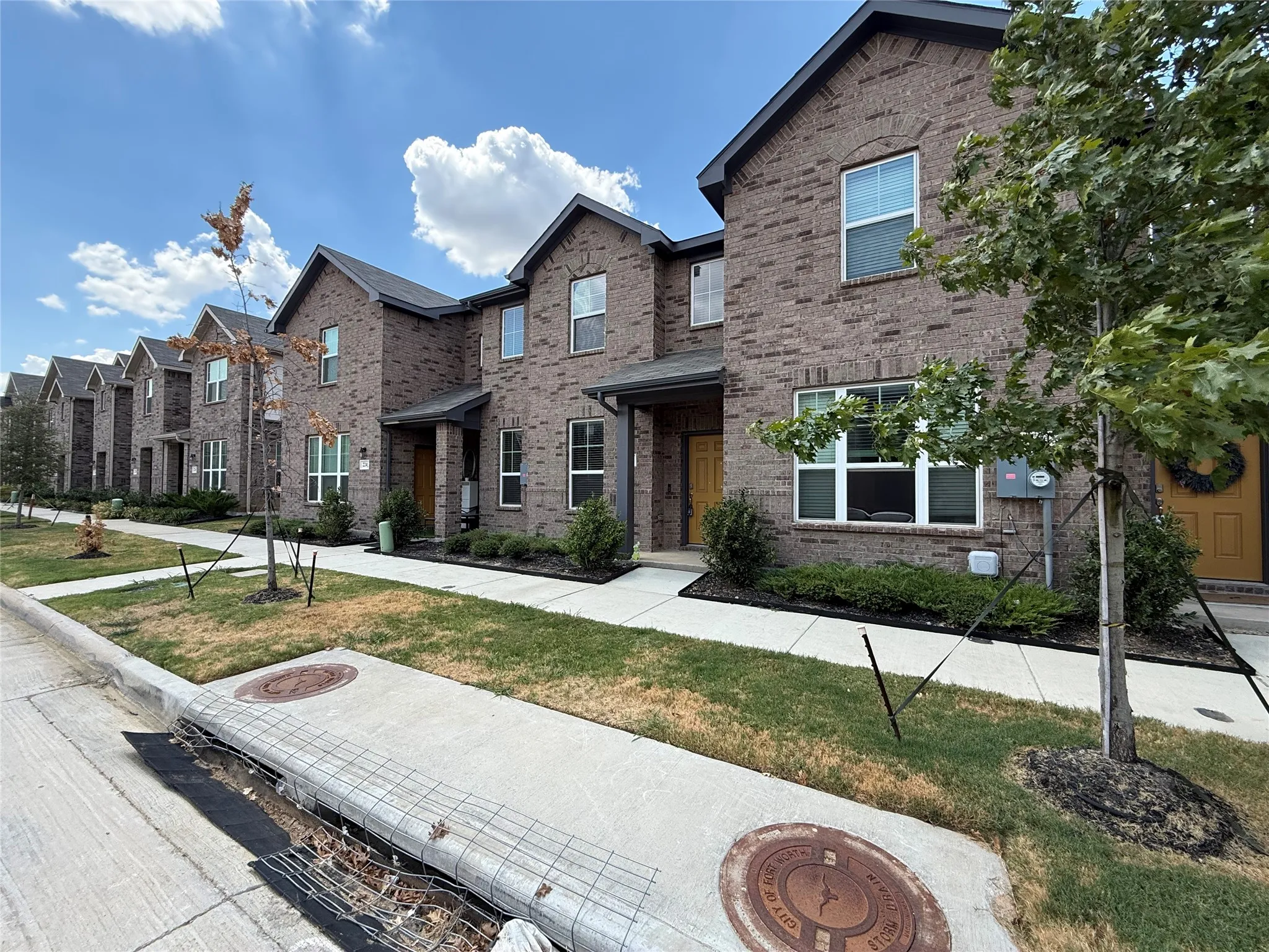 Brick exterior with dark gray shingles, white-framed windows, and a covered entryway