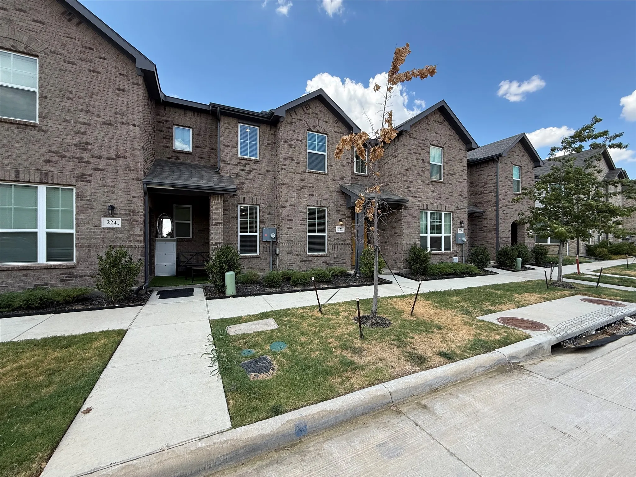 Brick exterior with dark gray gables, covered entryway, and front landscaping