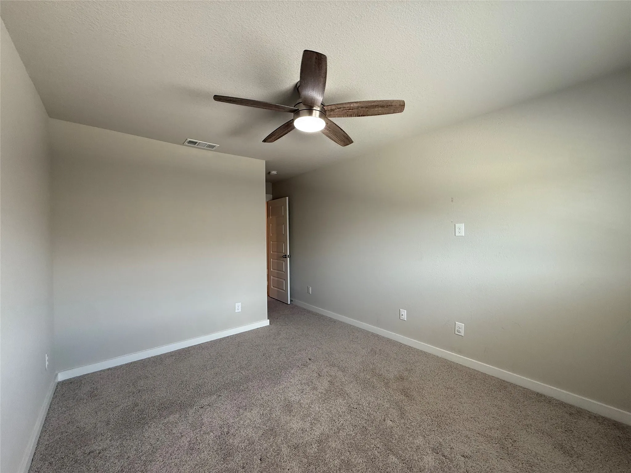 Neutral wall finishes with a ceiling-mounted fan fixture and carpeted flooring