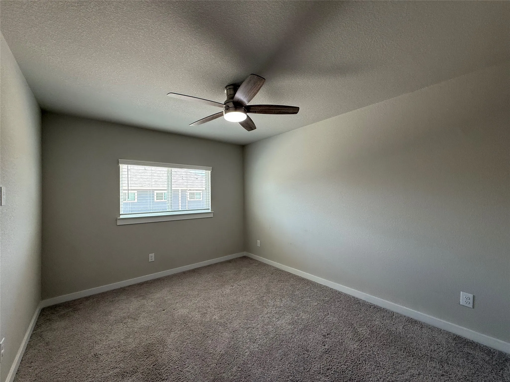 Neutral-toned walls, textured carpeting, contemporary ceiling fan with integrated lighting, and a window with blinds