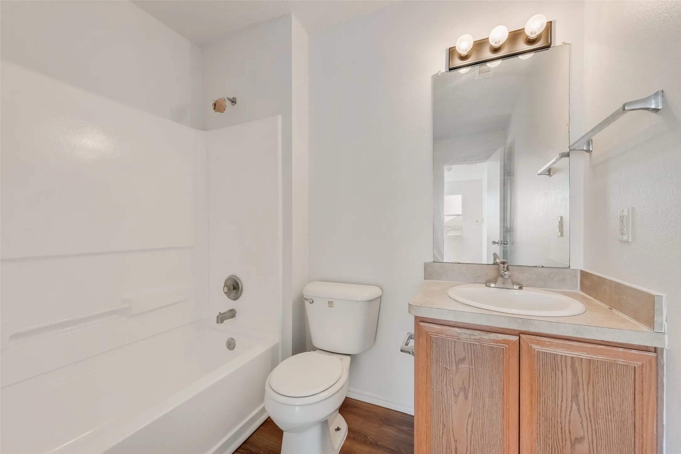 Bathroom featuring a tub/shower combination, a vanity with a laminate countertop, and wood-finish flooring